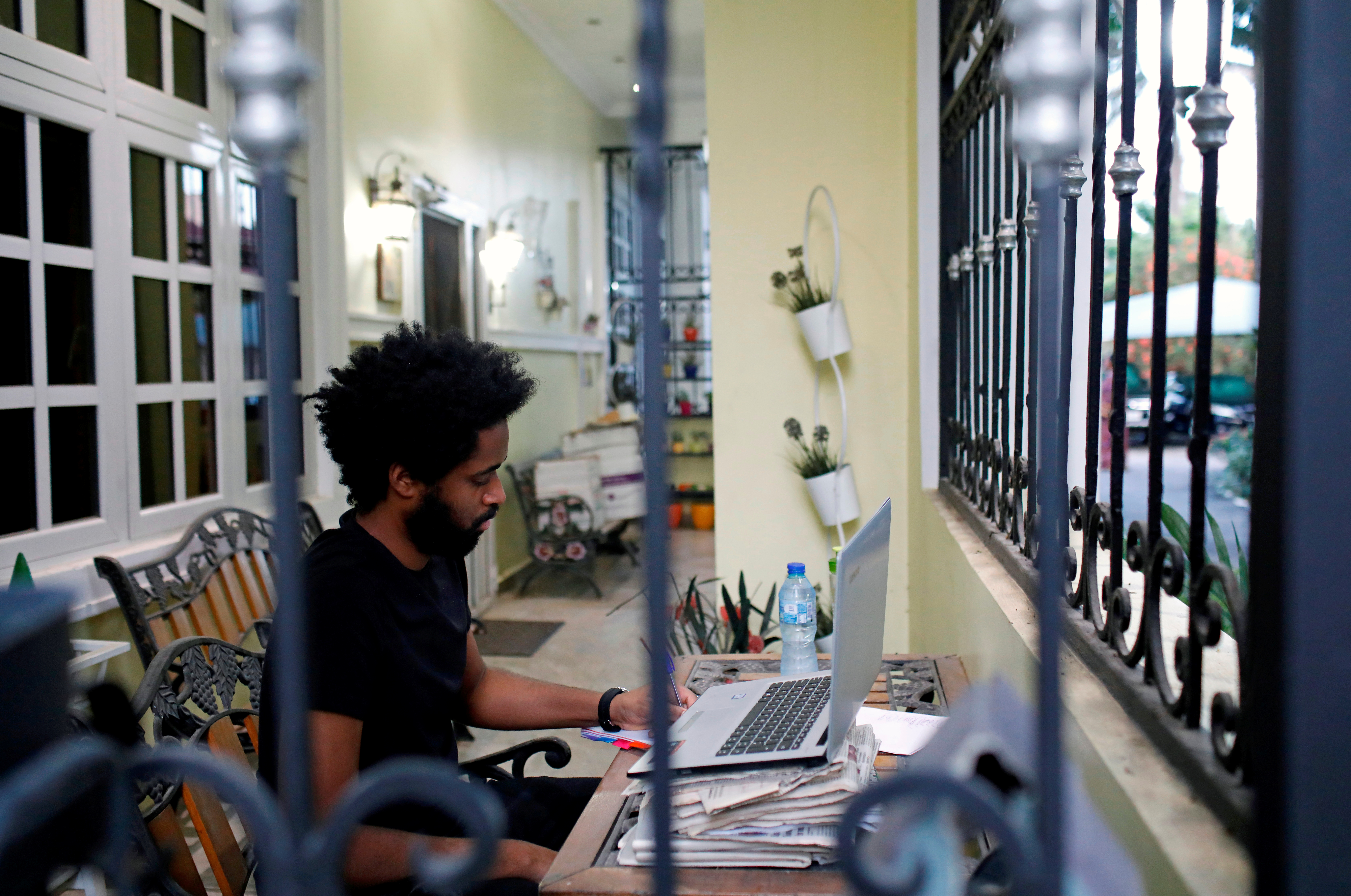 Alexander Caiafas, a 25 year-old data analyst, is seen working through a window into his home in Ikoyi, as authorities around the world impose various guidelines on lockdowns and social distancing to curb the spread of coronavirus disease (COVID-19), in Lagos, Nigeria May 25, 2020. When asked, what will you miss most about being in lockdown? Alexander replied: ' Spending quality time with relatives and parents because you know, thatÕs often hard to do. Secondly, I would say I miss speaking over the phone to close friends like on FaceTime, HouseParty, Zoom, all those kinds of applications'.  Picture taken May 25, 2020. REUTERS/Temilade Adelaja - RC2LXG98YSTW