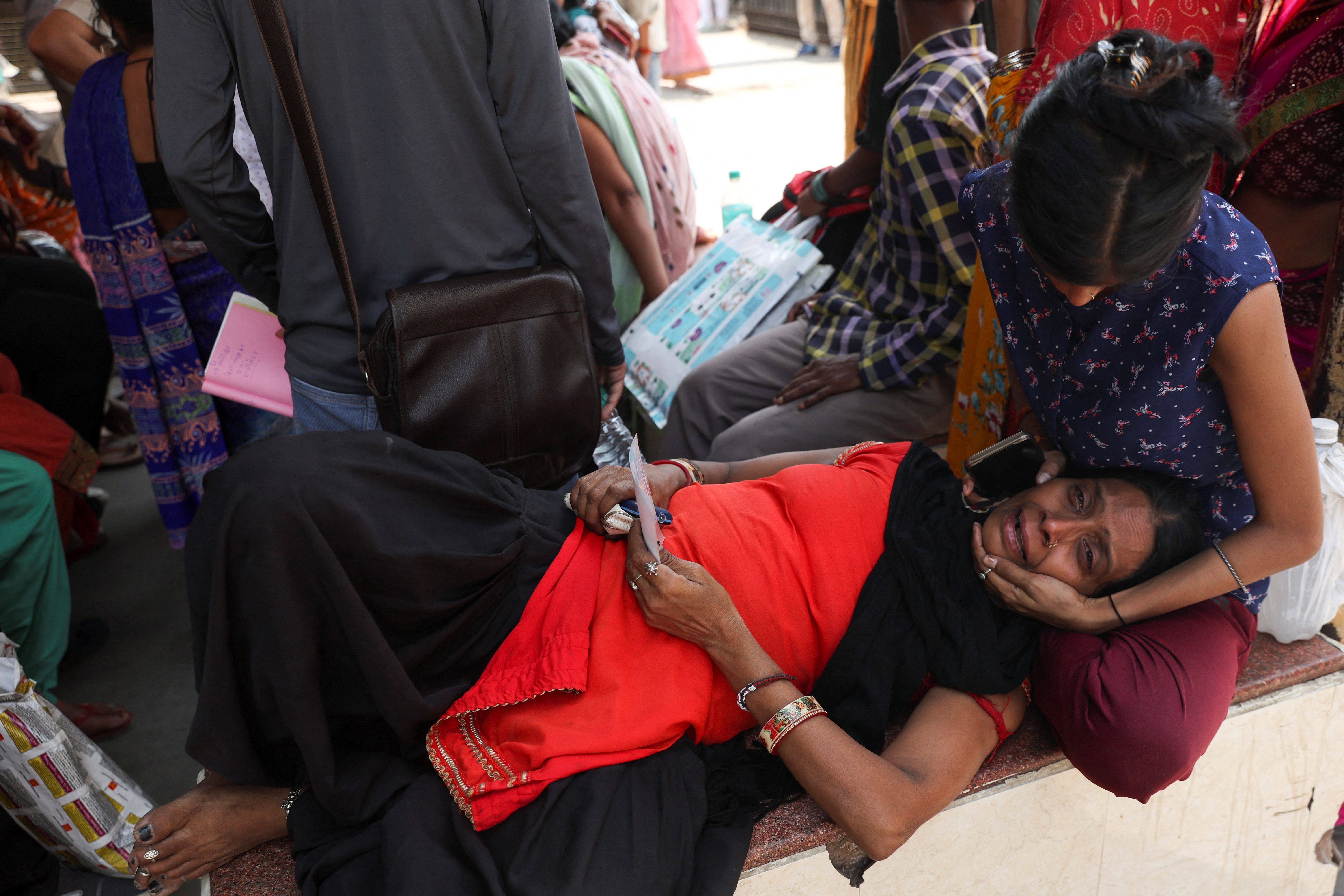 Woman consoles her mother as they wait to identify Komal's sister body after the fire that broke out in a commercial building in New Delhi