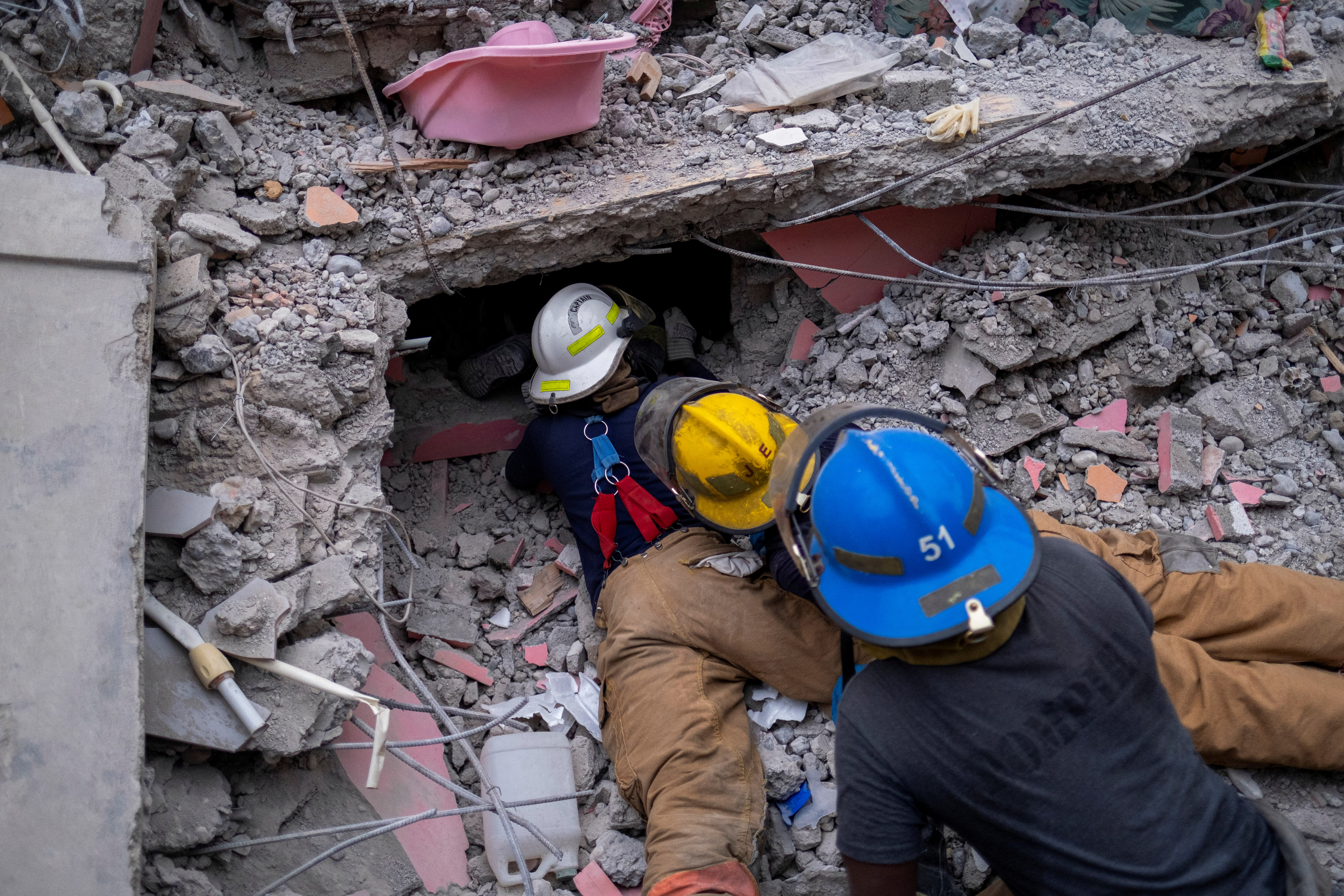 Haitian firefighters search for survivors, under the rubble of a destroyed hotel, after Saturday's 7.2 magnitude quake, in Les Cayes, Haiti August 16, 2021. REUTERS/Ricardo Arduengo