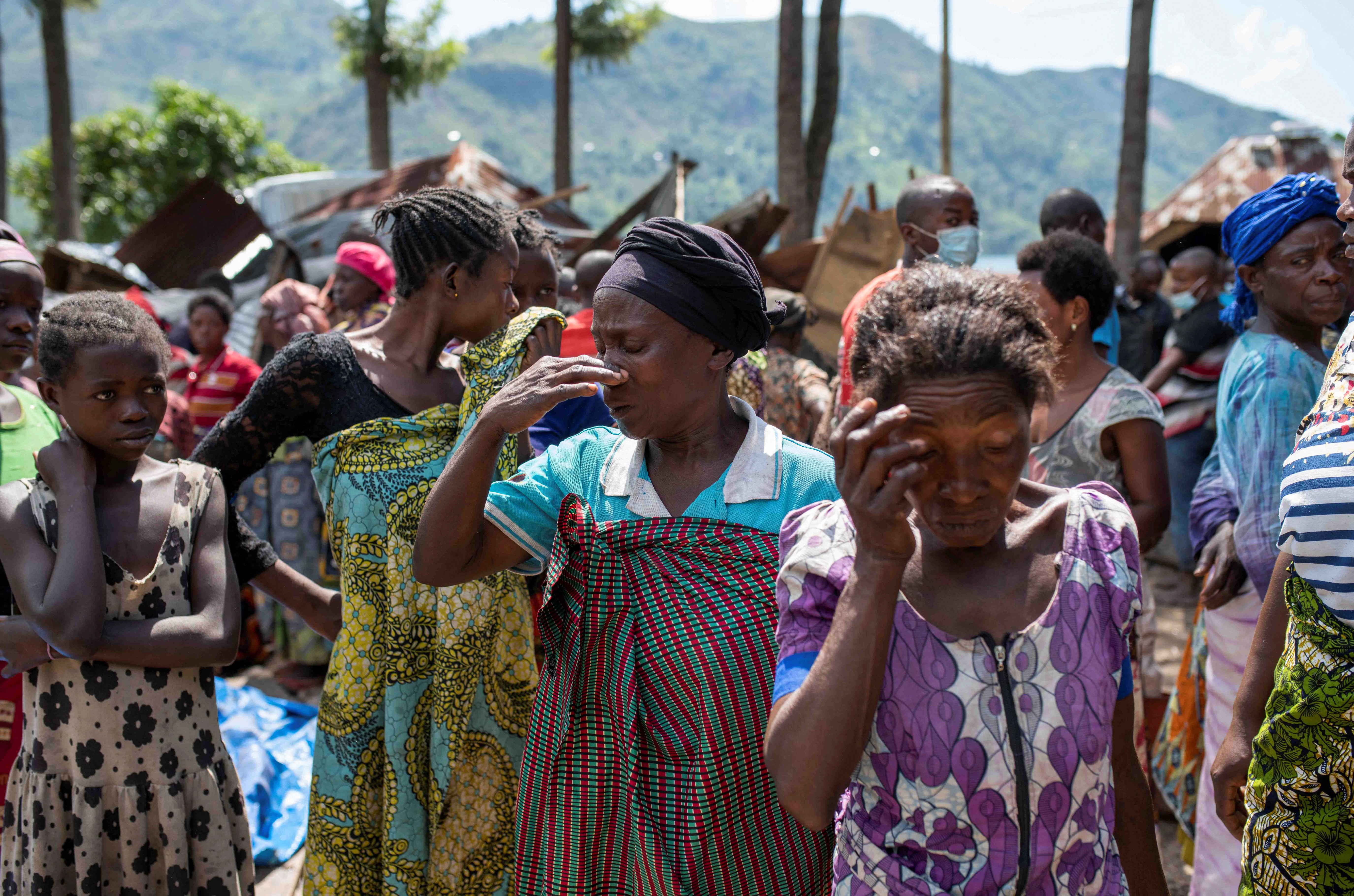 Congolese women react after the death of their family members following rains that destroyed buildings and forced aid workers to gather mud-clad corpses into piles in the village of Nyamukubi
