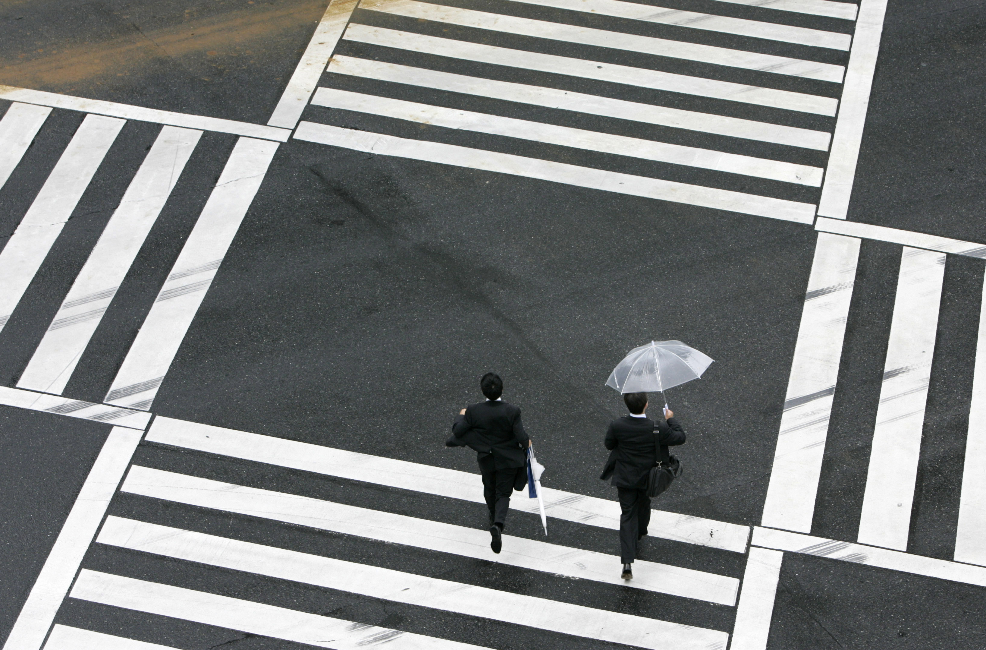 Businessmen run as they cross a street in Tokyo