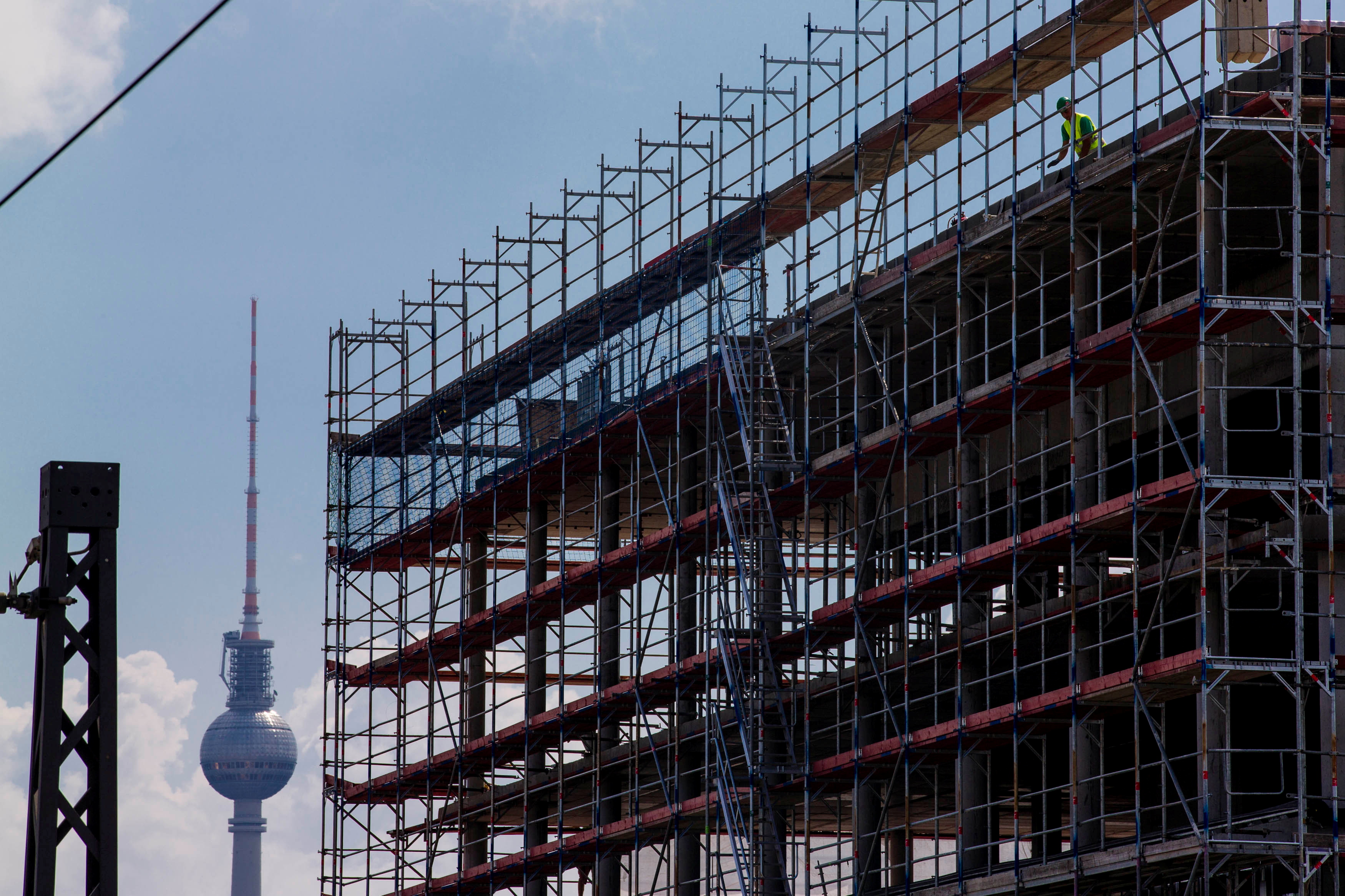 A worker is seen behind scaffoldings at a construction site in Berlin