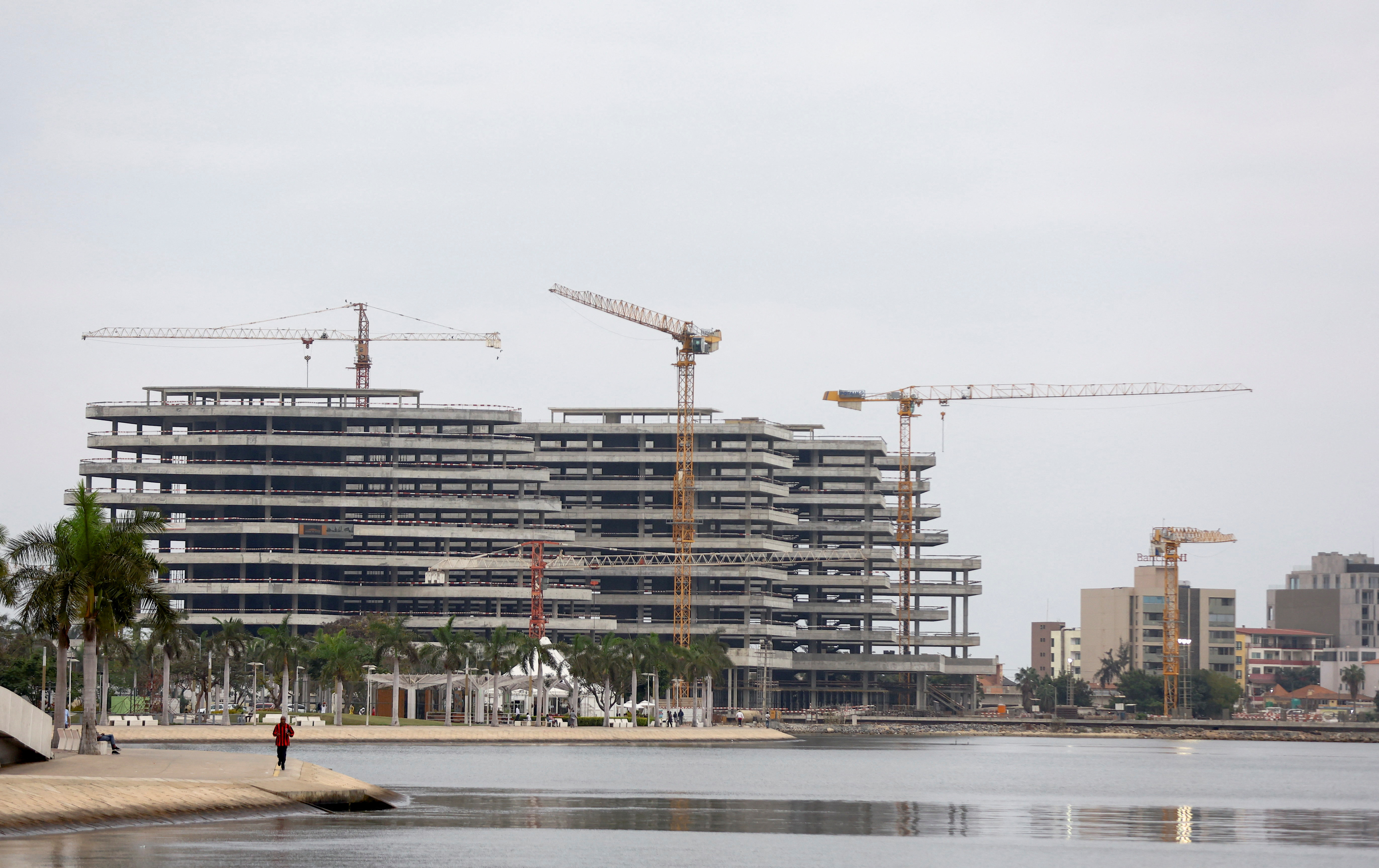 A man jogs as office buildings under construction are seen in the distance, in Luanda