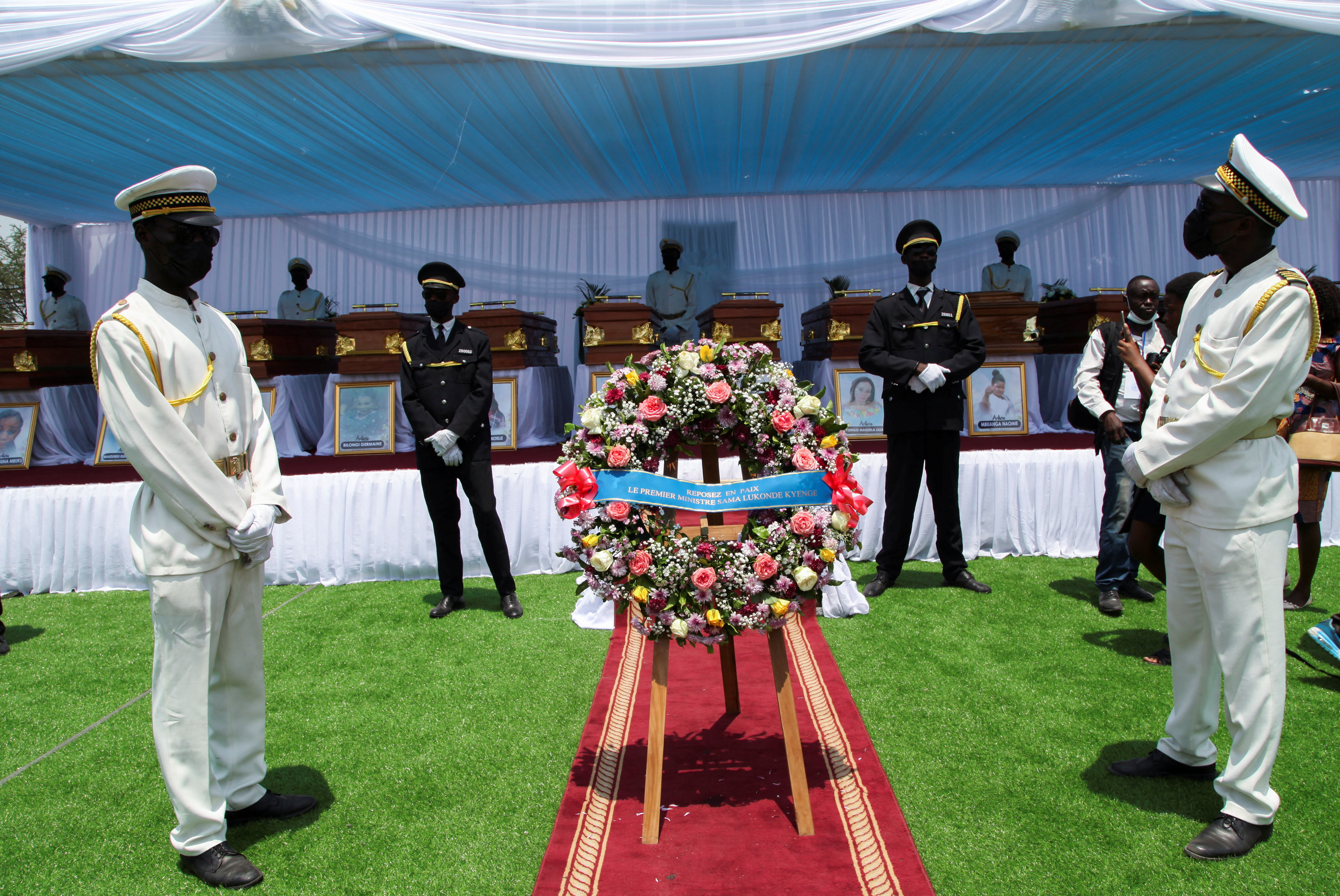 Funeral service workers stand beside coffins during a mass funeral for 25 people who were killed when a high-voltage power cable snapped and fell on houses and market, at the Velodrome stadium in Kinshasa,