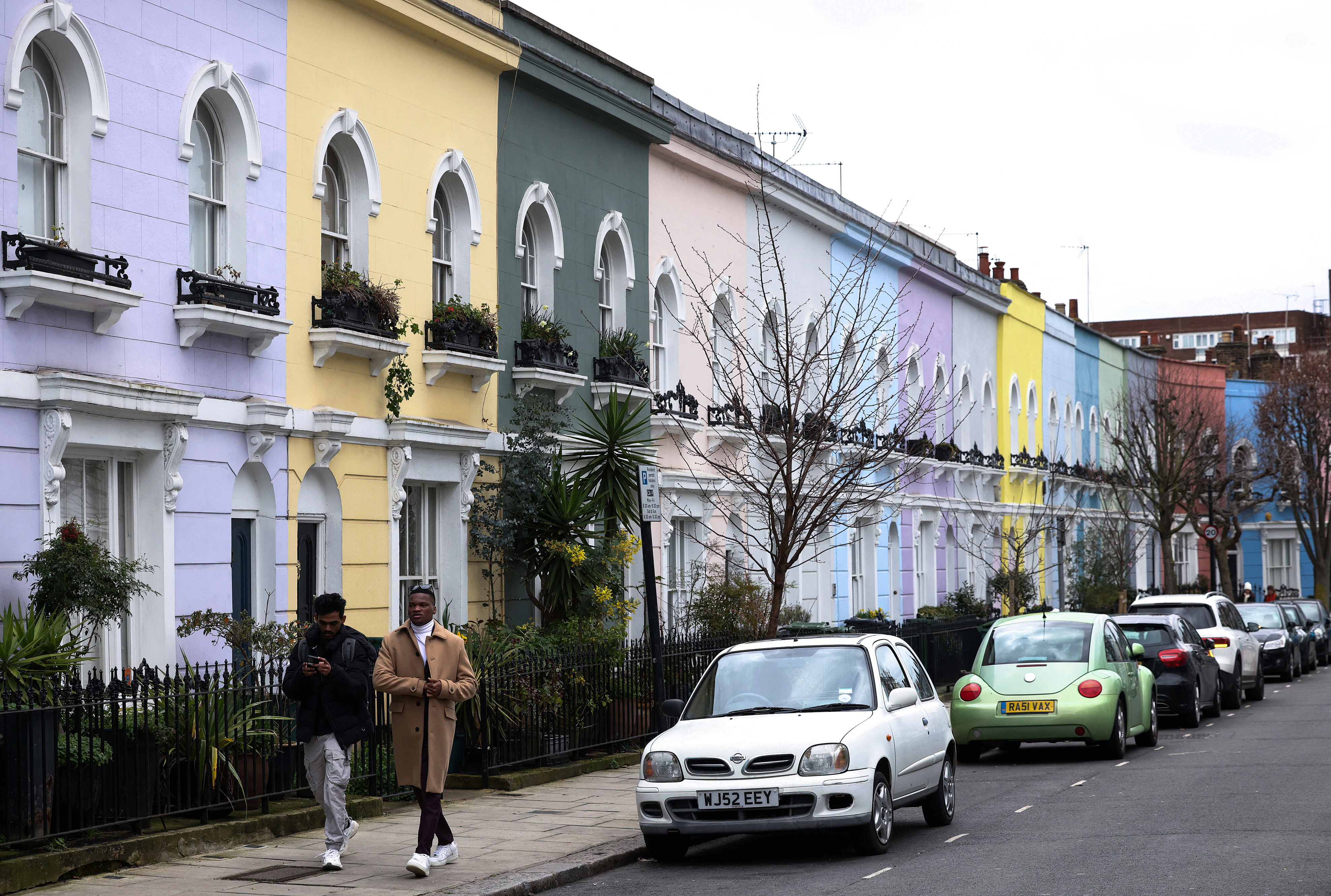 People walk past a row of colourful houses in London