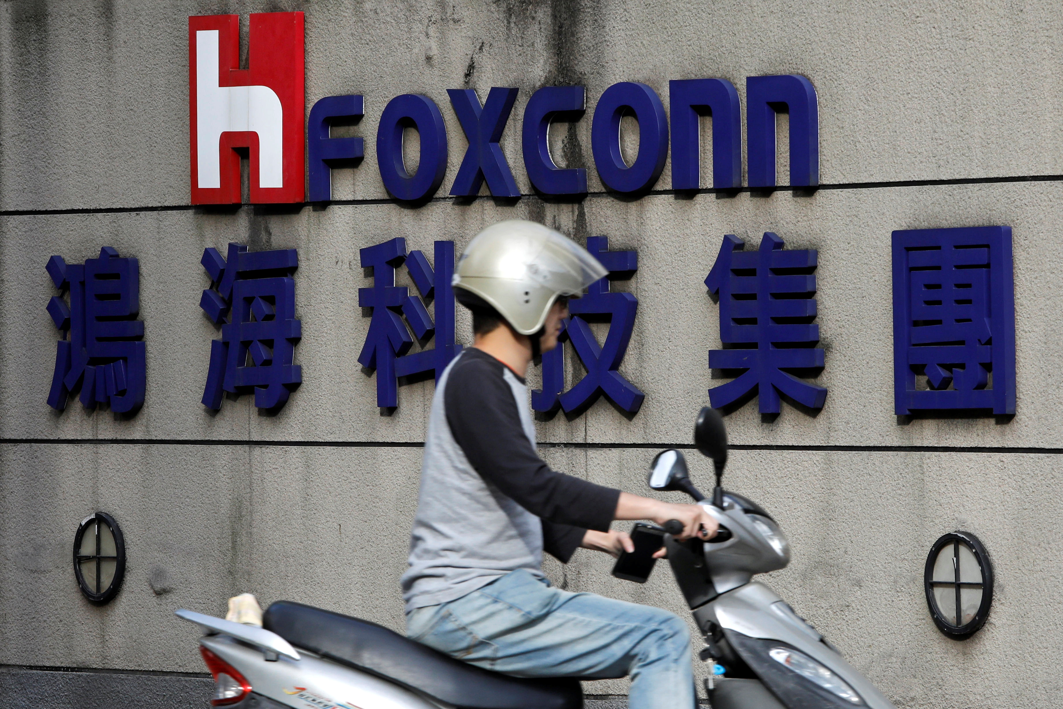 A motorcyclist rides past the logo of Foxconn, the trading name of Hon Hai Precision Industry, in Taipei