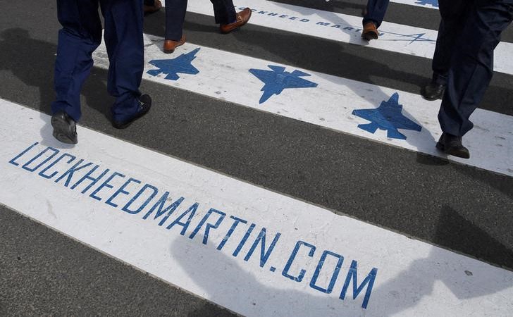 Trade visitors are seen walking over a road crossing covered with Lockheed Martin branding at Farnborough International Airshow in Farnborough, Britain