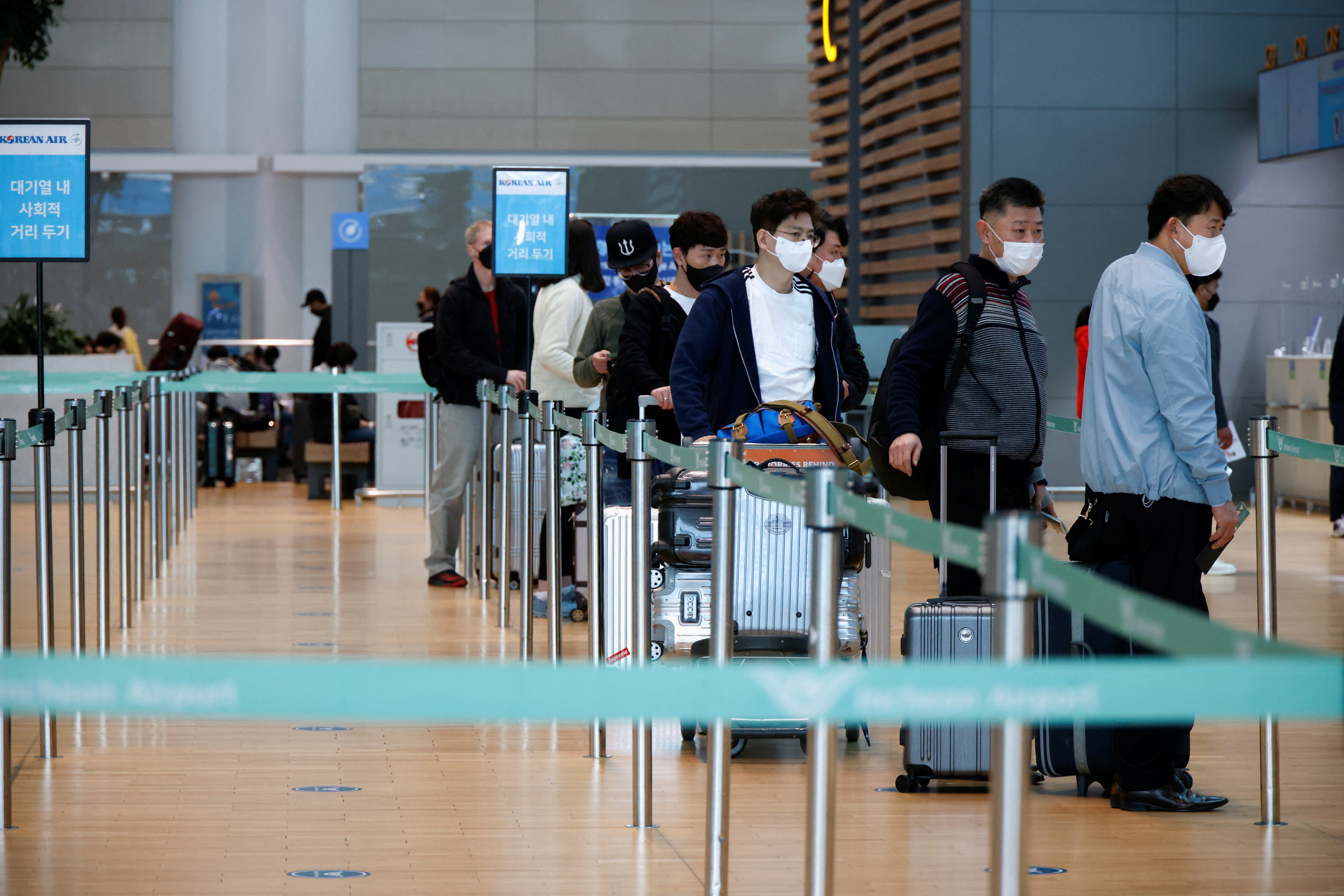 People wearing face masks to prevent from contracting the coronavirus disease (COVID-19) wait in line to check in at Incheon International Airport, in Incheon, South Korea