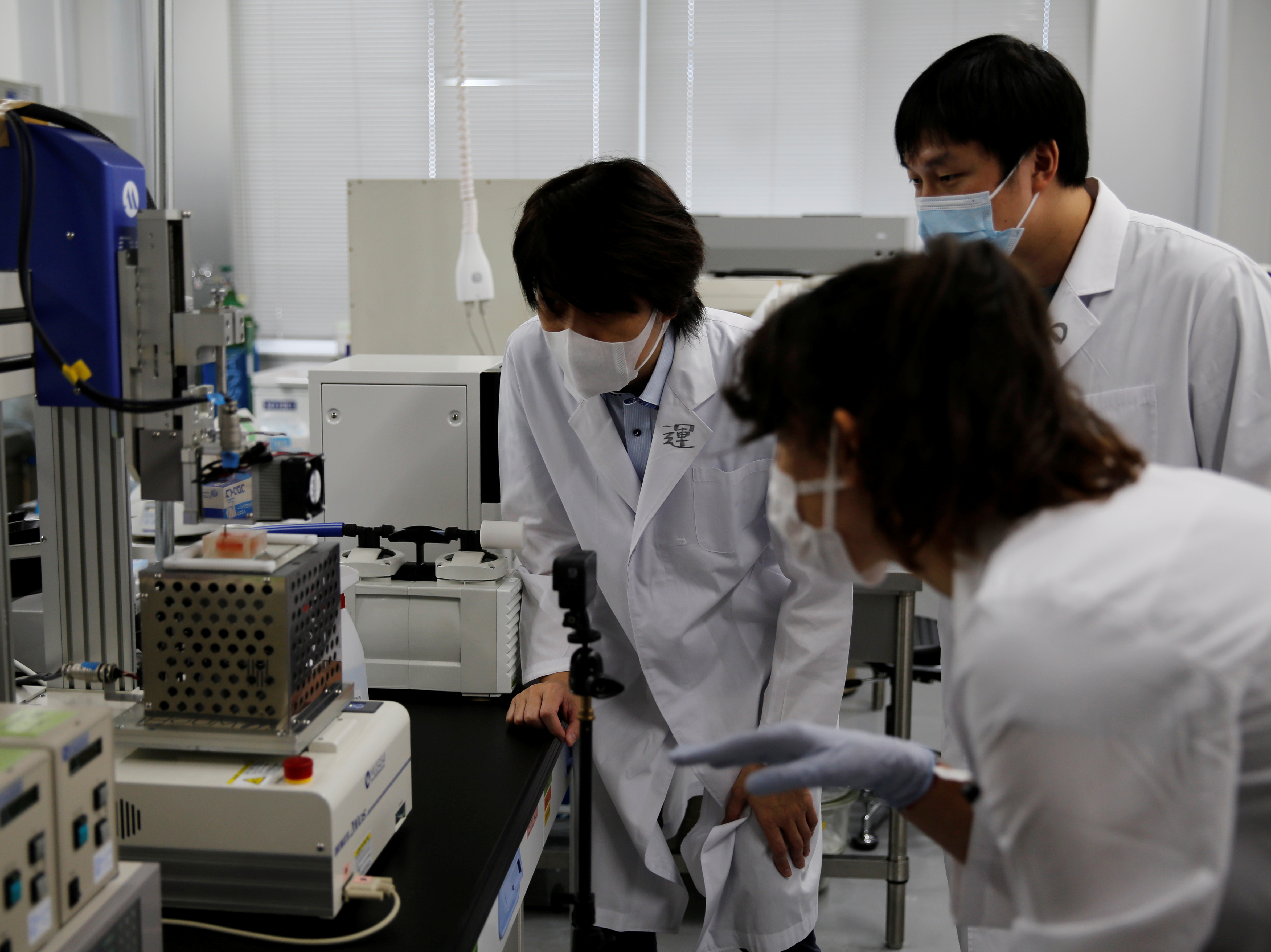 Osaka University Professor Matsusaki and fellow researchers look at a 3-D printer at a lab at the university in Suita