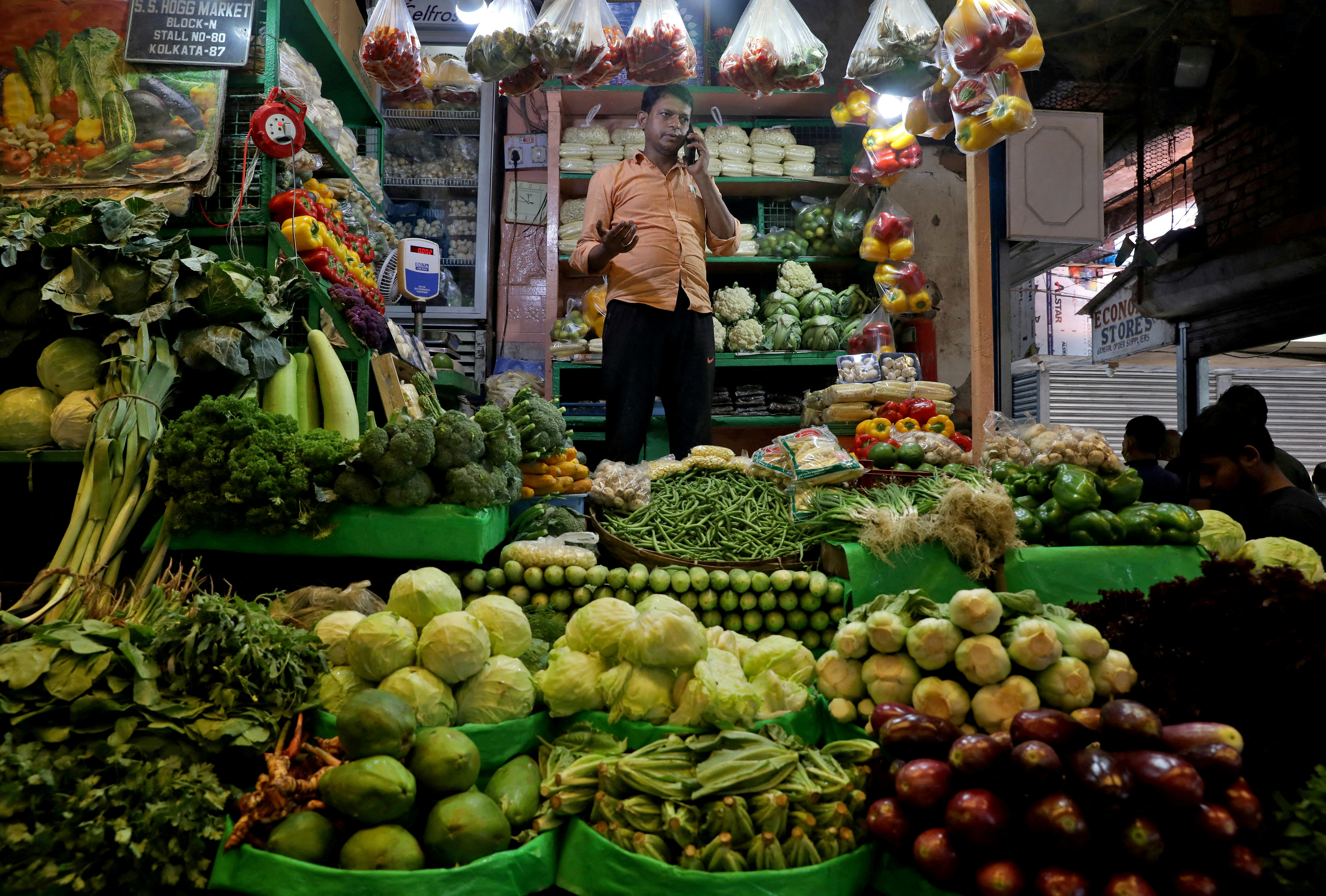 A vegetable vendor speaks on his mobile phone at a retail market area in Kolkata