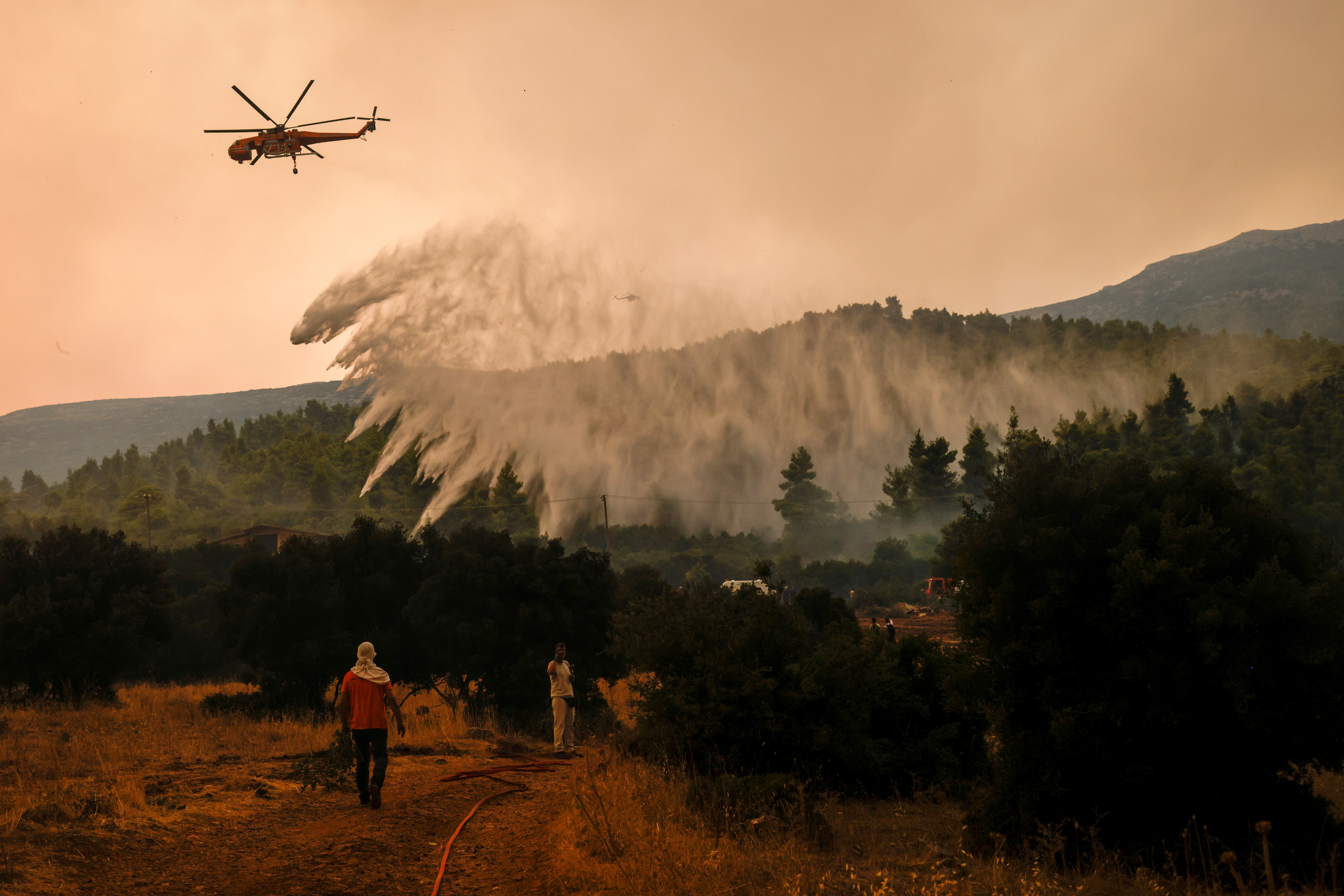 A firefighting helicopter makes a water drop as a wildfire burns in the village of Vilia, Greece, August 18, 2021. REUTERS/Alkis Konstantinidis