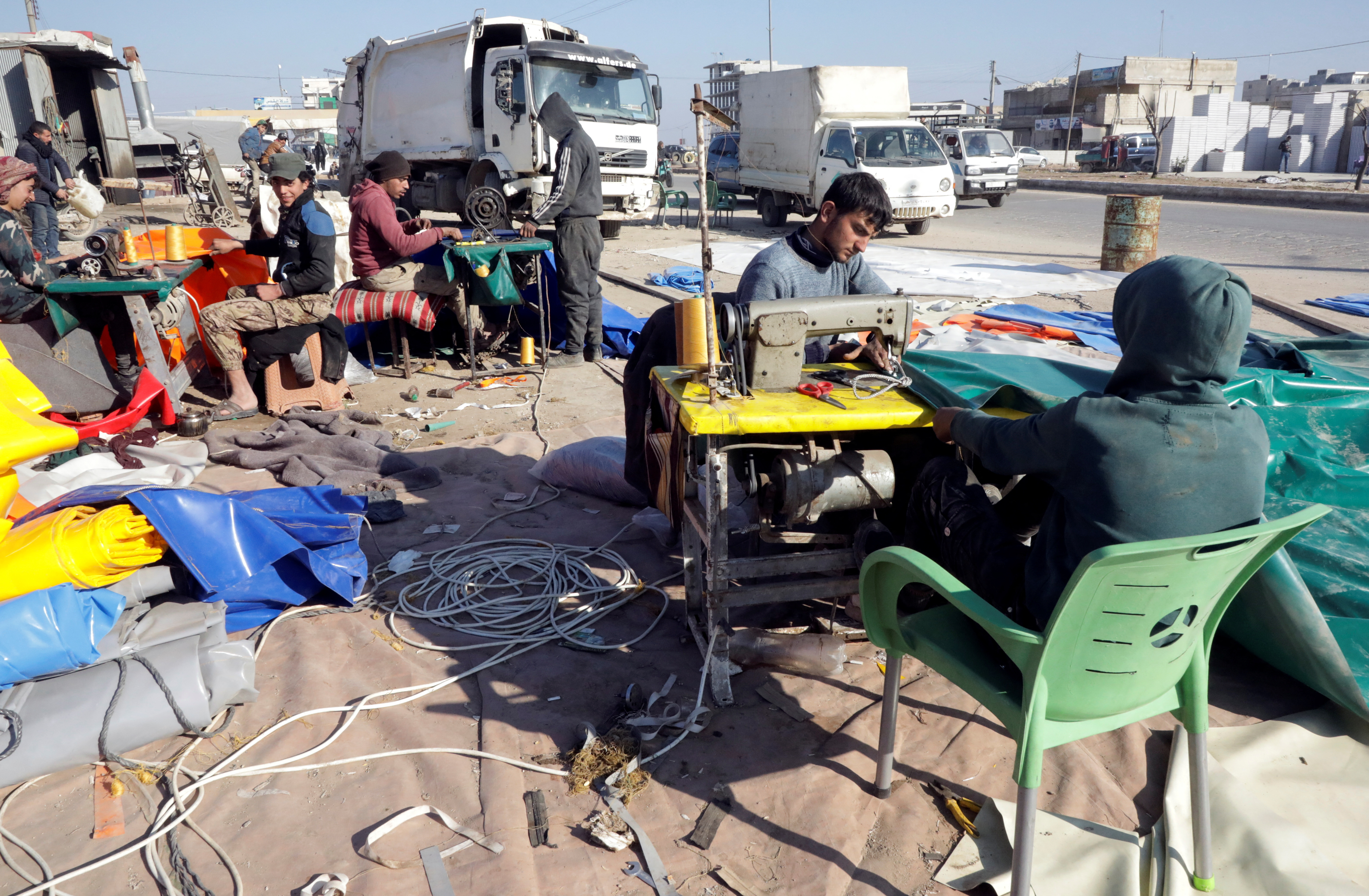 Workers use sewing machines at a tent manufacturing workshop in Azaz