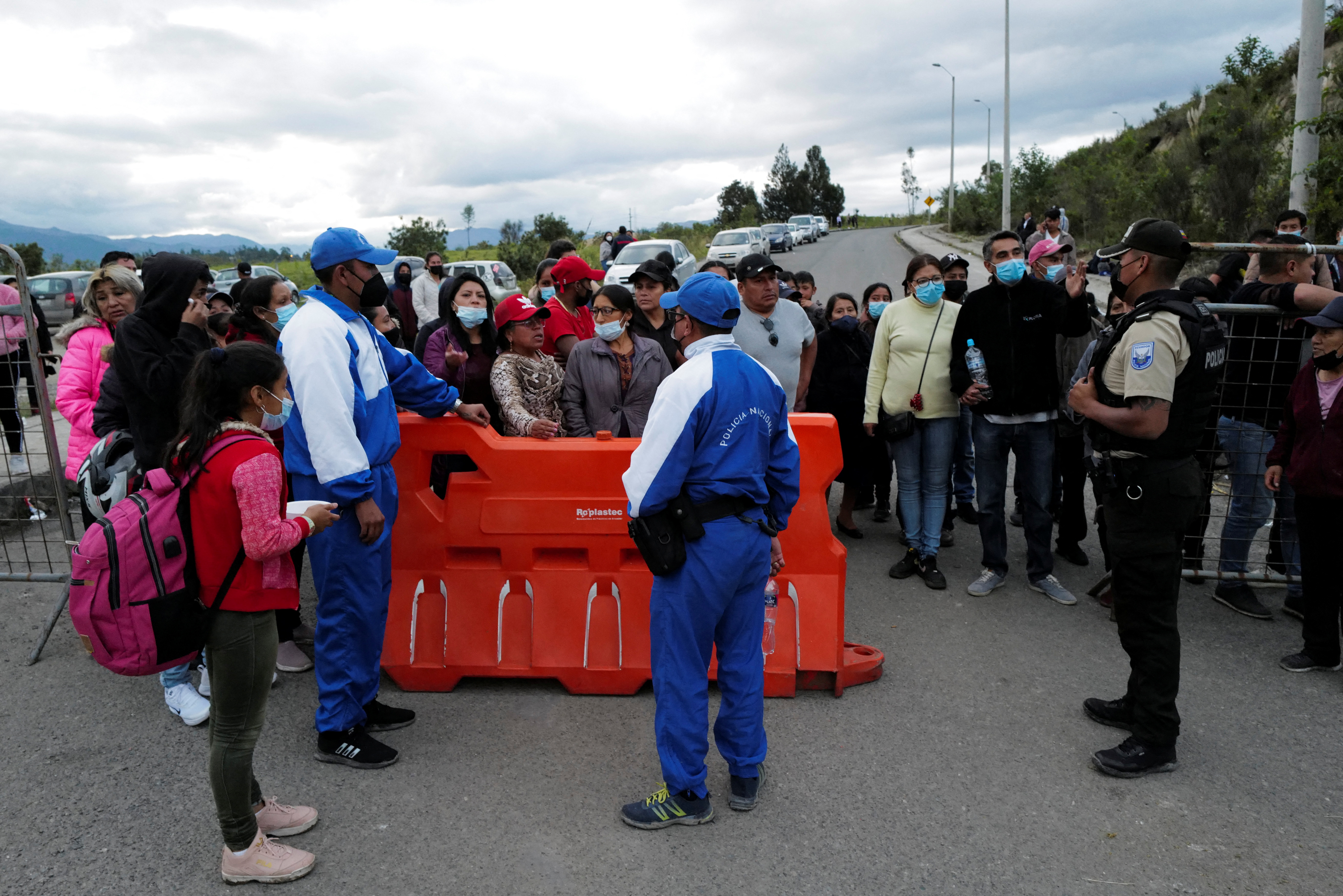 Relatives of inmates stand at a police checkpoint waiting for news of their loved ones after a riot broke out at the El Turi prison where several inmates were killed or injured, in Cuenca