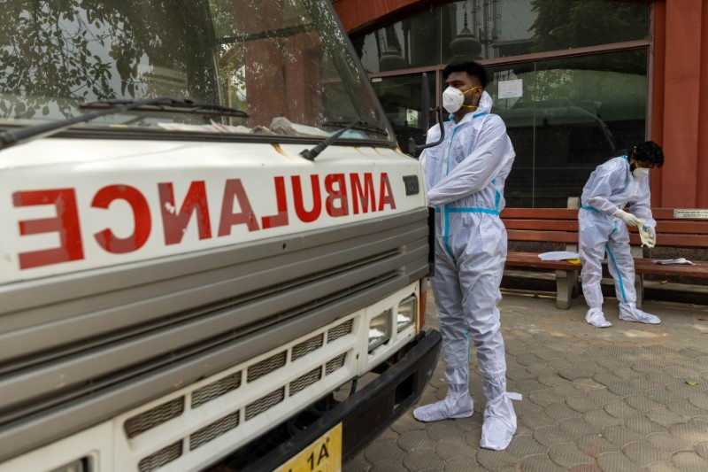 Health workers wear personal protective equipment (PPE) as they prepare to carry the body of a person, who died from complications related to the coronavirus disease (COVID-19), for cremation at a crematorium in New Delhi