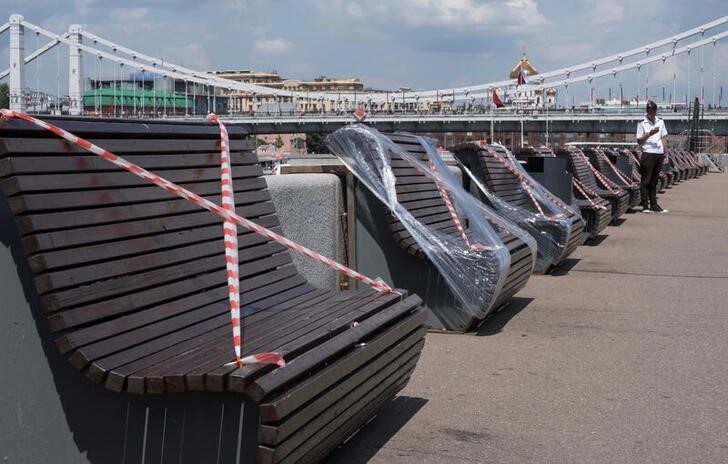 A boat tours vendor uses his mobile phone near taped-off benches in Moscow