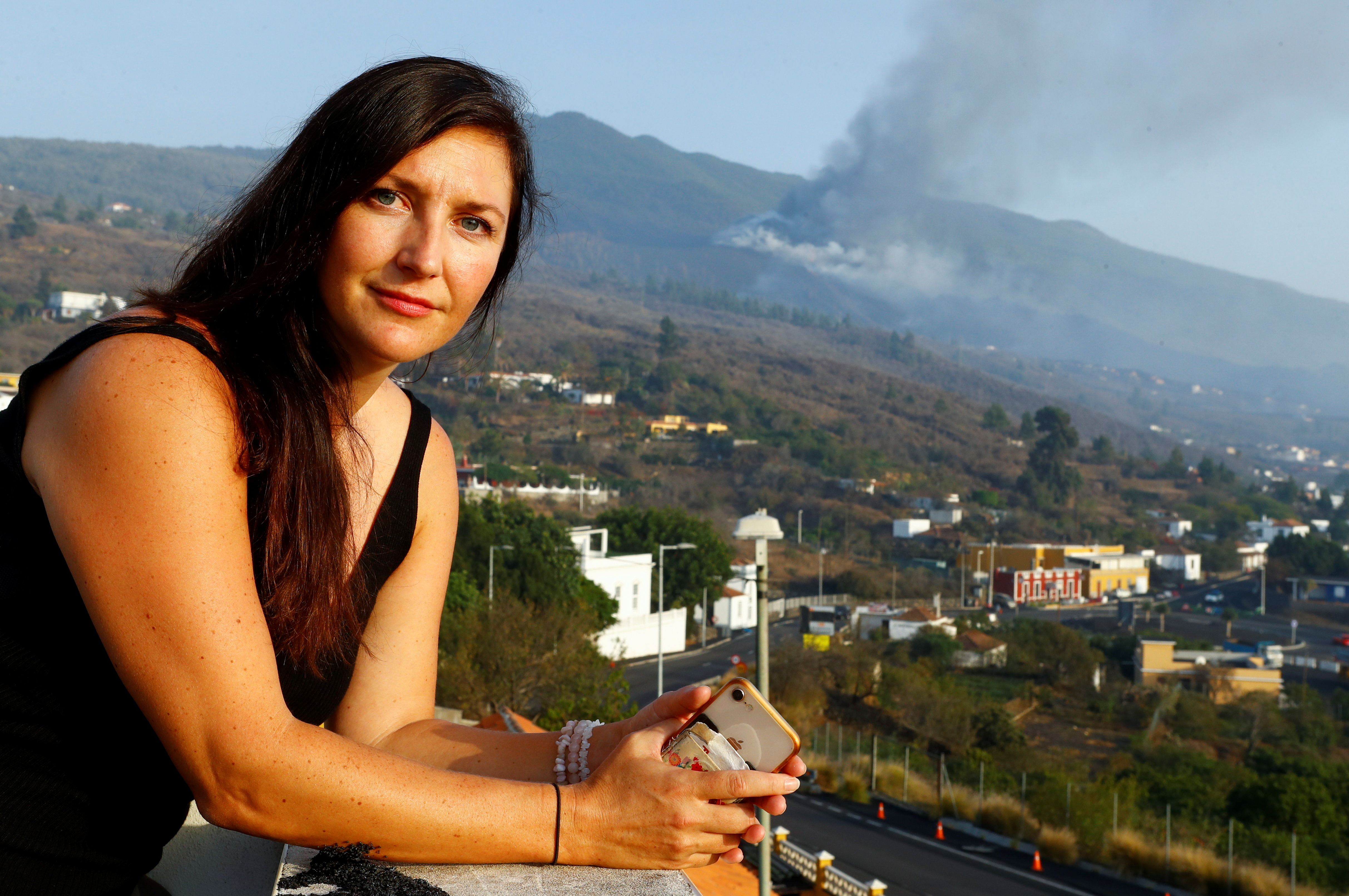 Czech Eva Kubelkova, a volcano fanatic based in the Azores, poses for a picture with the Cumbre Vieja volcano in the background, in El Paso