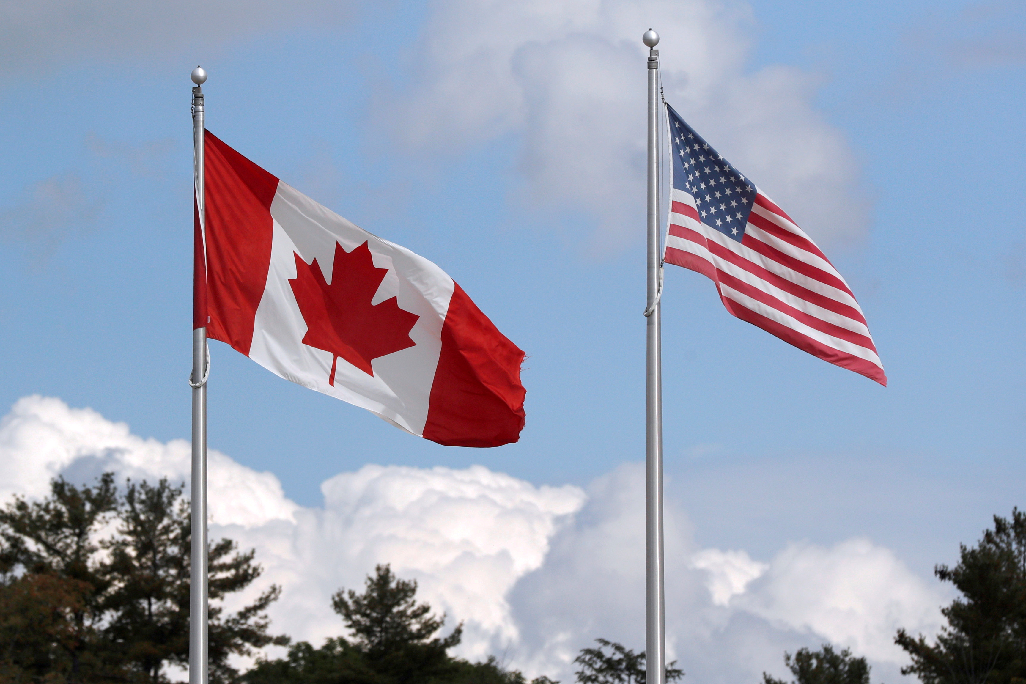A U.S. and a Canadian flag flutter at the Canada-United States border crossing at the Thousand Islands Bridge, which remains closed to non-essential traffic to combat the spread of the coronavirus disease (COVID-19) in Lansdowne, Ontario, Canada September 28, 2020. REUTERS/Lars Hagberg/File Photo
