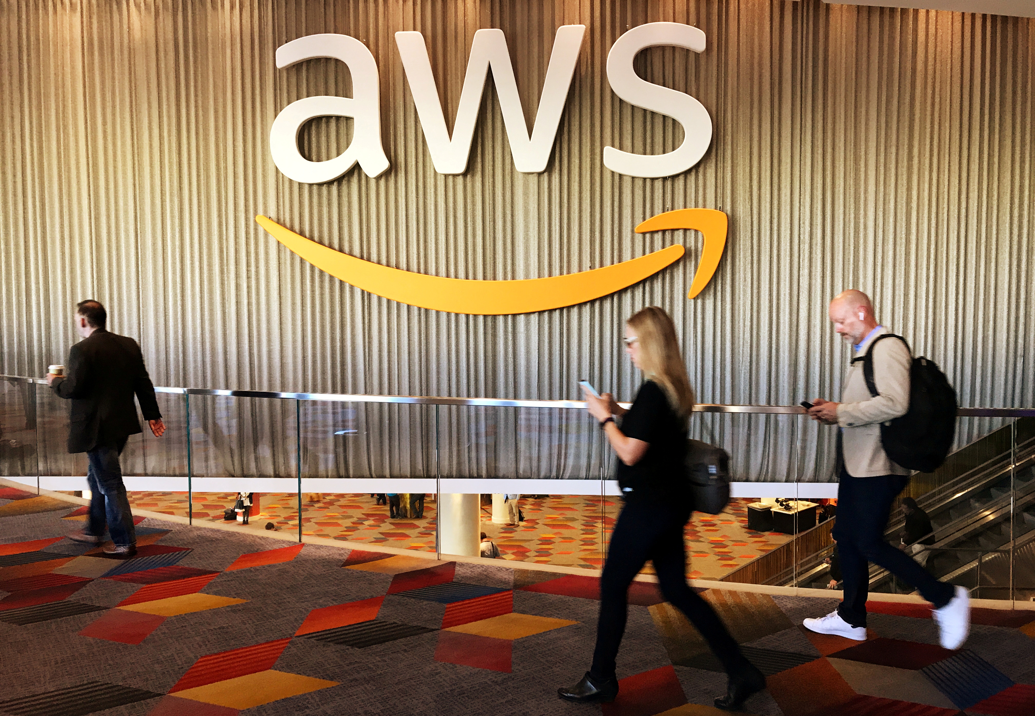 Attendees at Amazon.com Inc annual cloud computing conference walk past the Amazon Web Services logo in Las Vegas