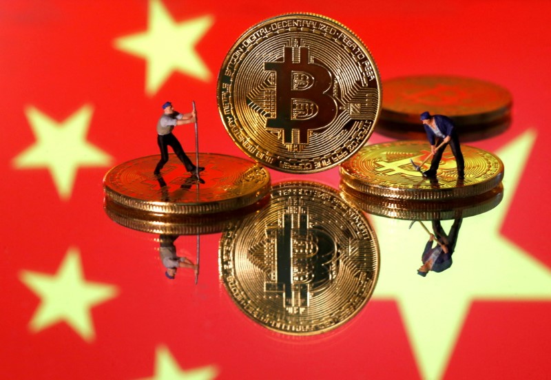 Picture illustration of small toy figurines and representations of the Bitcoin virtual currency displayed in front of an image of China's flag