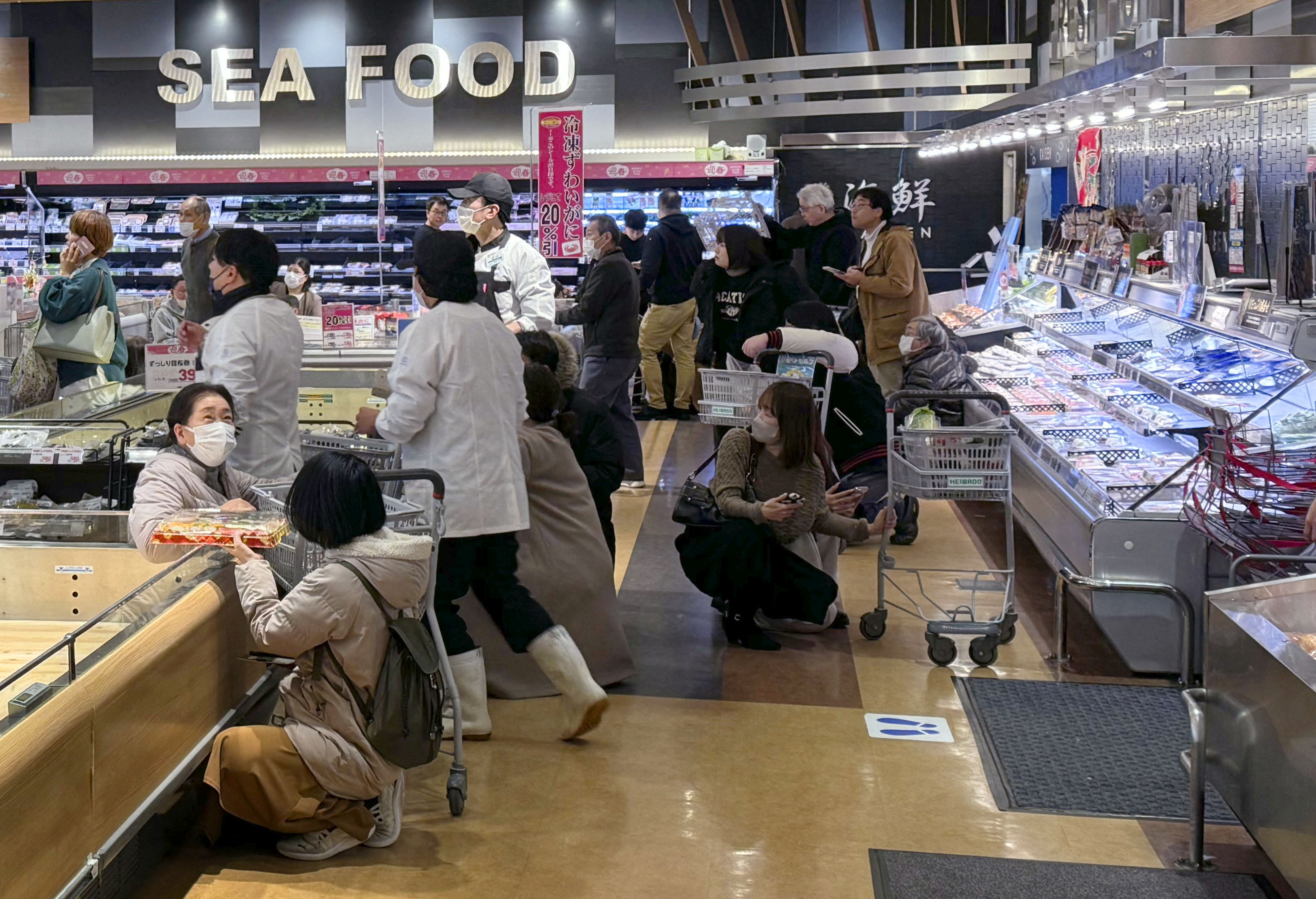 Shoppers crouch down as an earthquake hit the region at a supermarket in Toyama