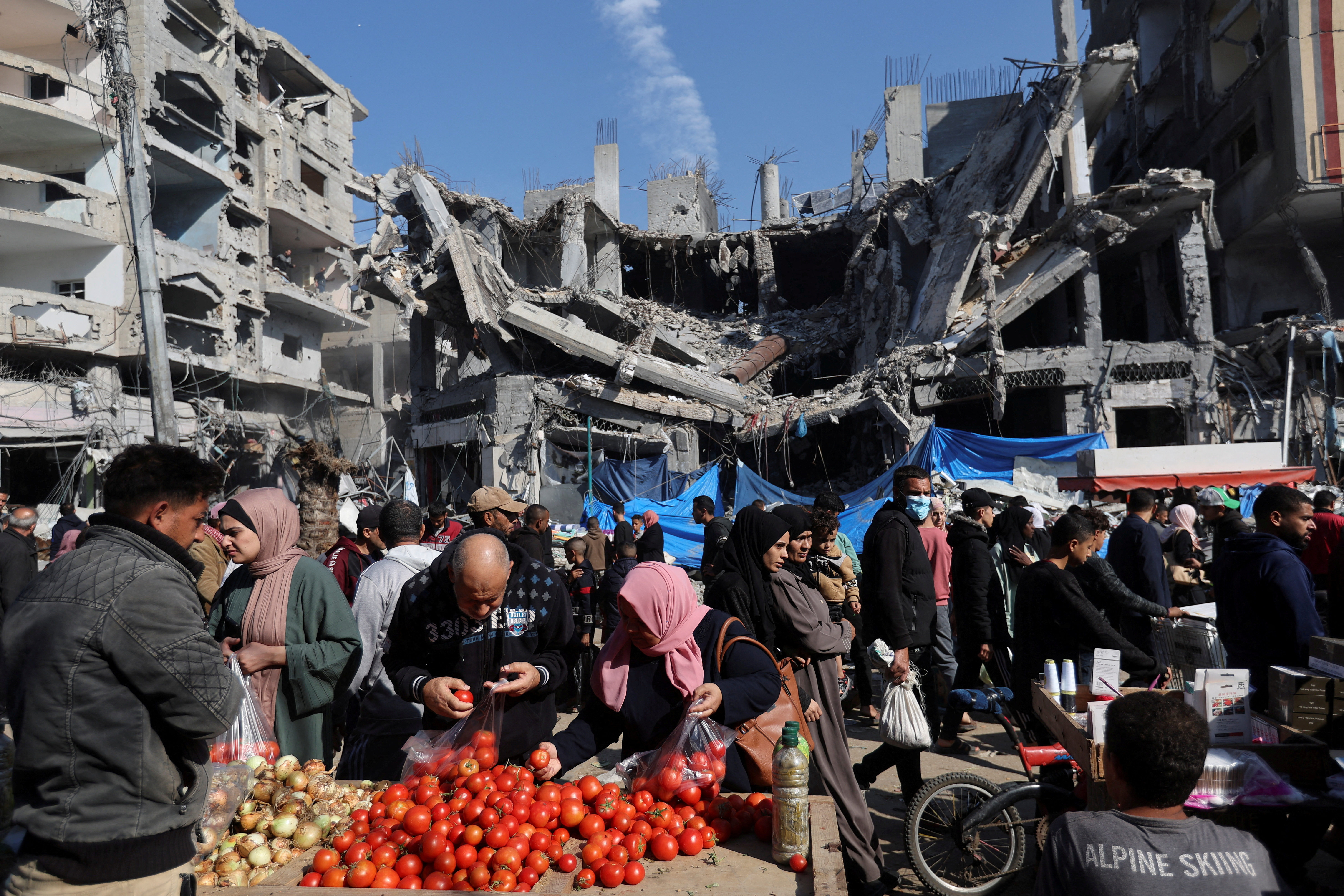 Palestinians shop near the ruins of houses and buildings destroyed in Israeli strikes during the conflict