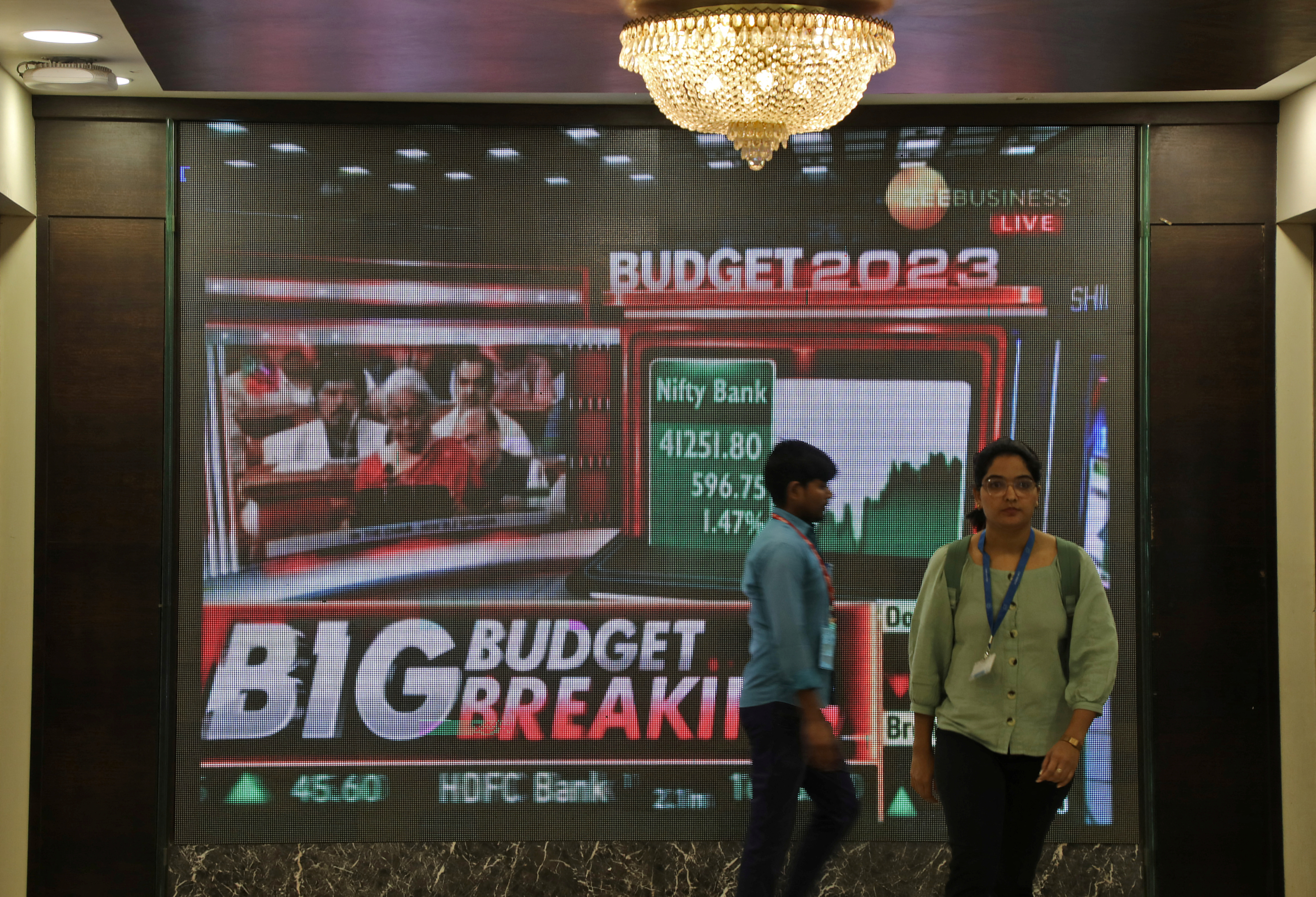 People walk past a telecast of India's Finance Minister Sitharaman presenting the budget, inside BSE in Mumbai