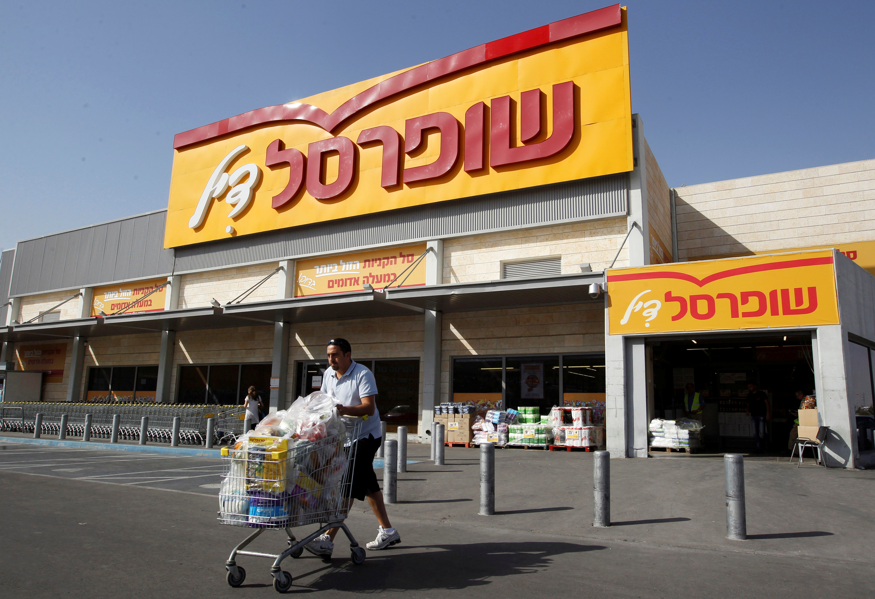 A man pushes a shopping cart outside Shufersal in the West Bank Jewish settlement of Mishor Adumim near Jerusalem