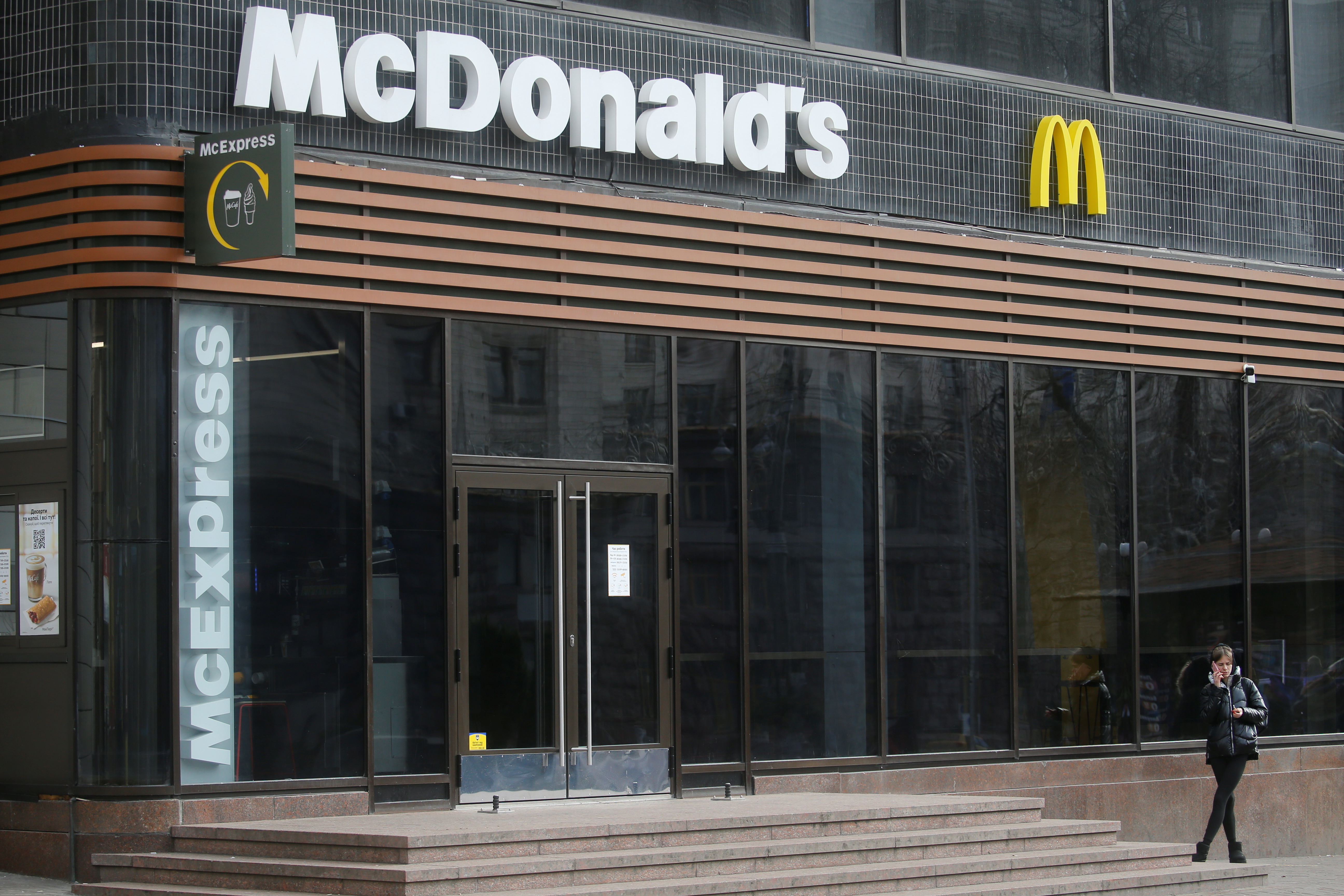 A woman speaks on the phone outside a closed McDonald's restaurant in Kyiv