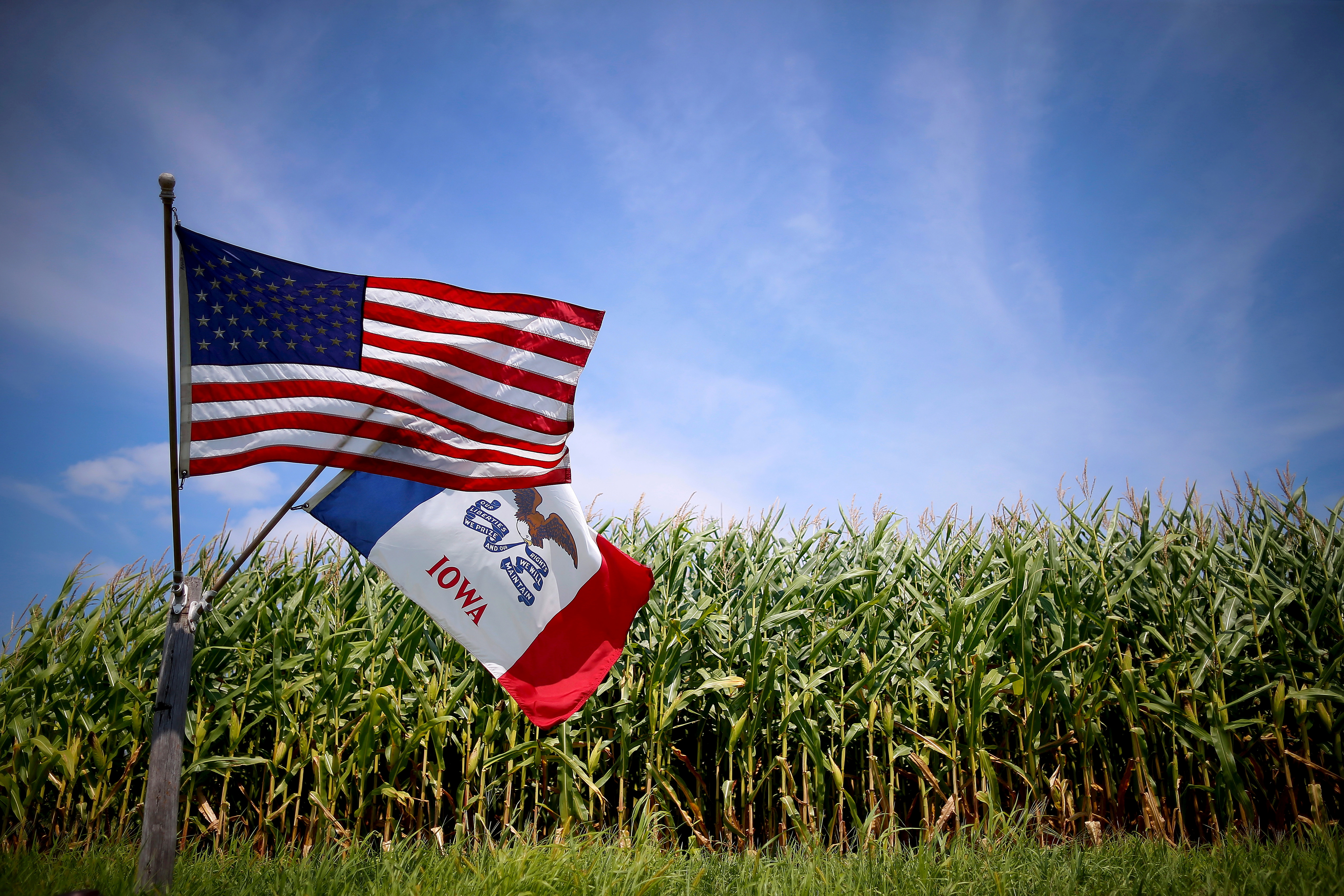A U.S. and Iowa state flag are seen next to a corn field in Grand Mound