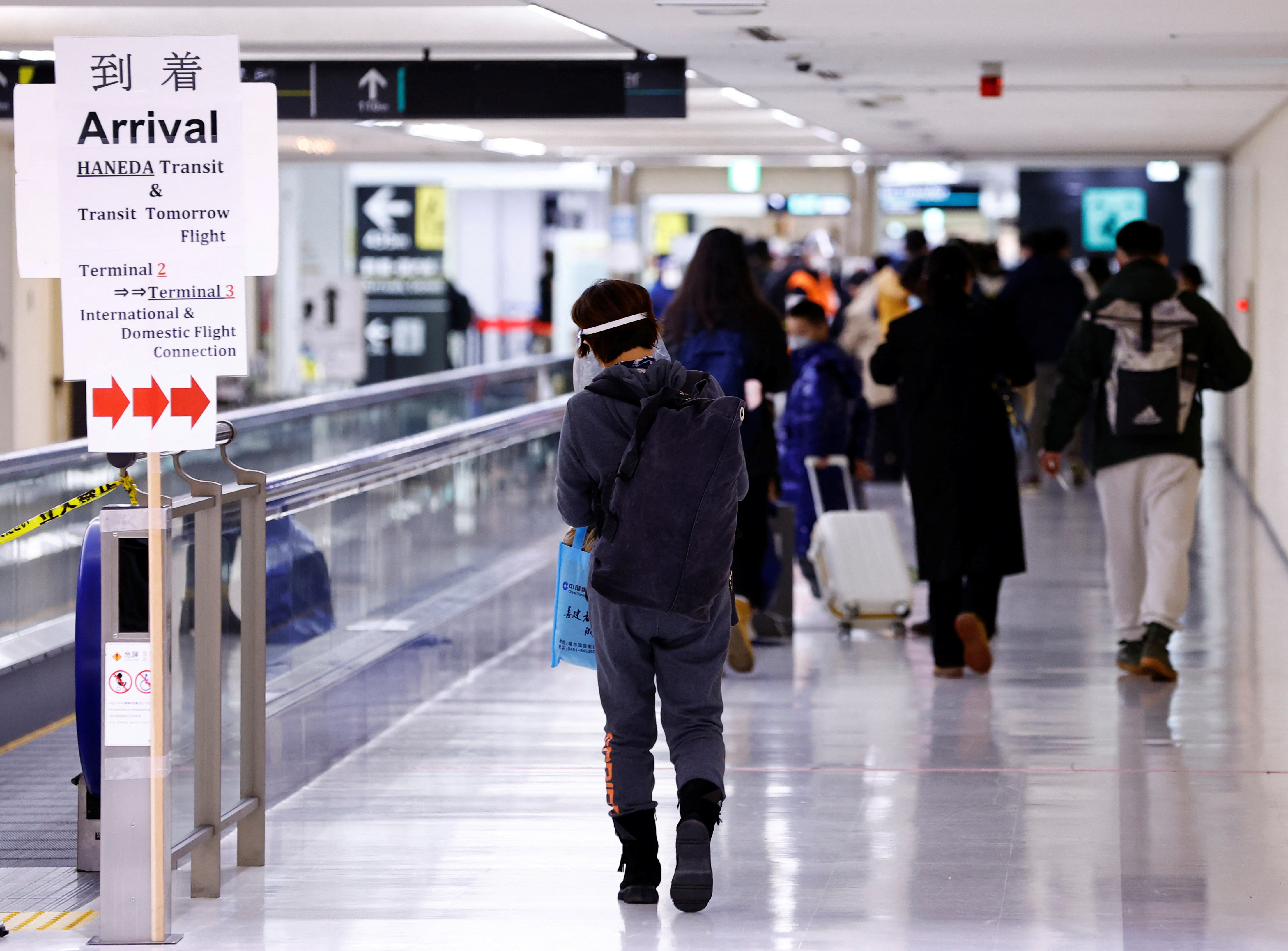 Passengers of a plane from Dalian in China, head to the coronavirus disease (COVID-19) test area, upon their arrival at Narita international airport