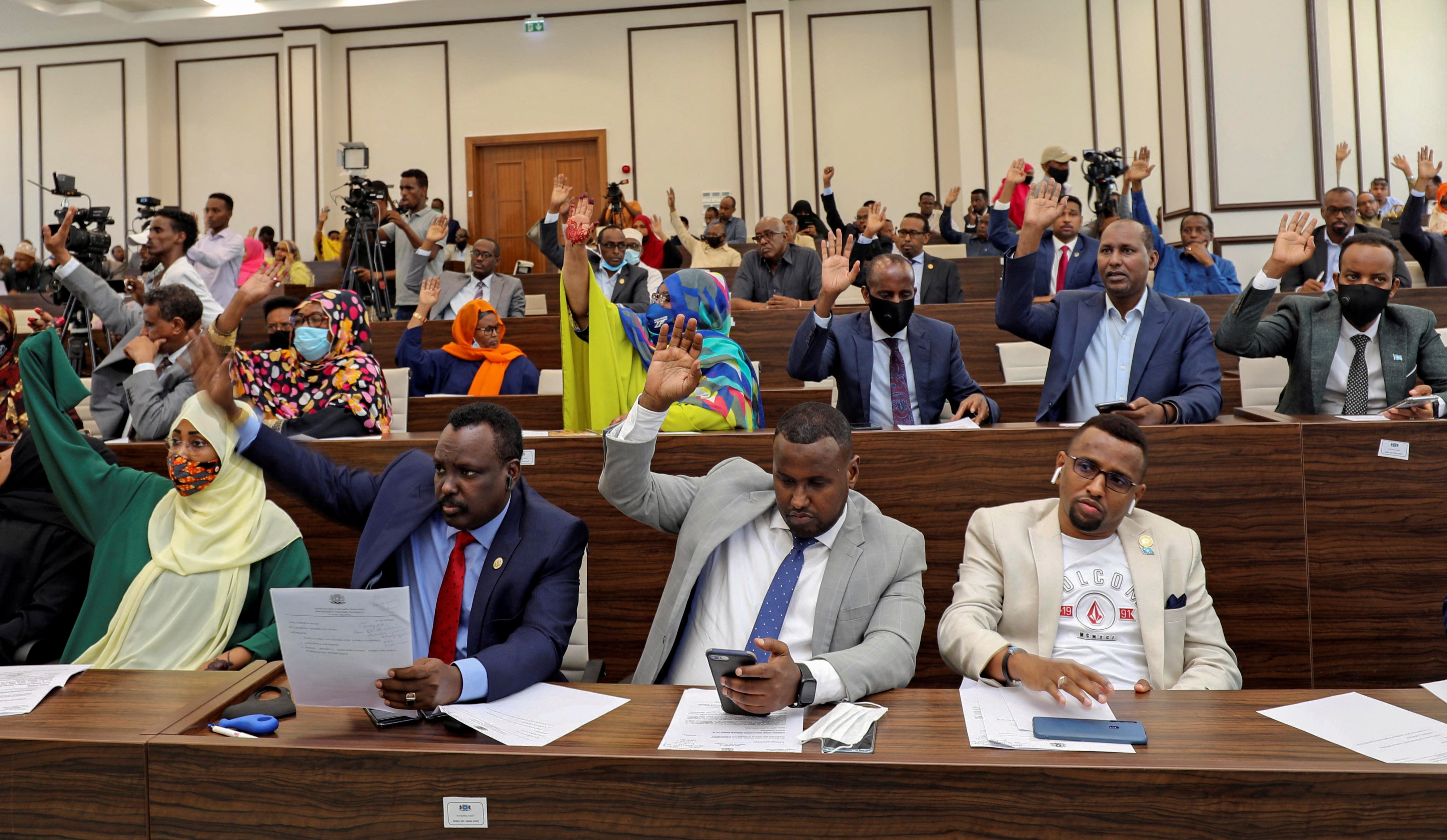 Somalia legislators vote by rising their hands to cancel a divisive two-year presidential term extension, inside the lower house of Parliament in Mogadishu