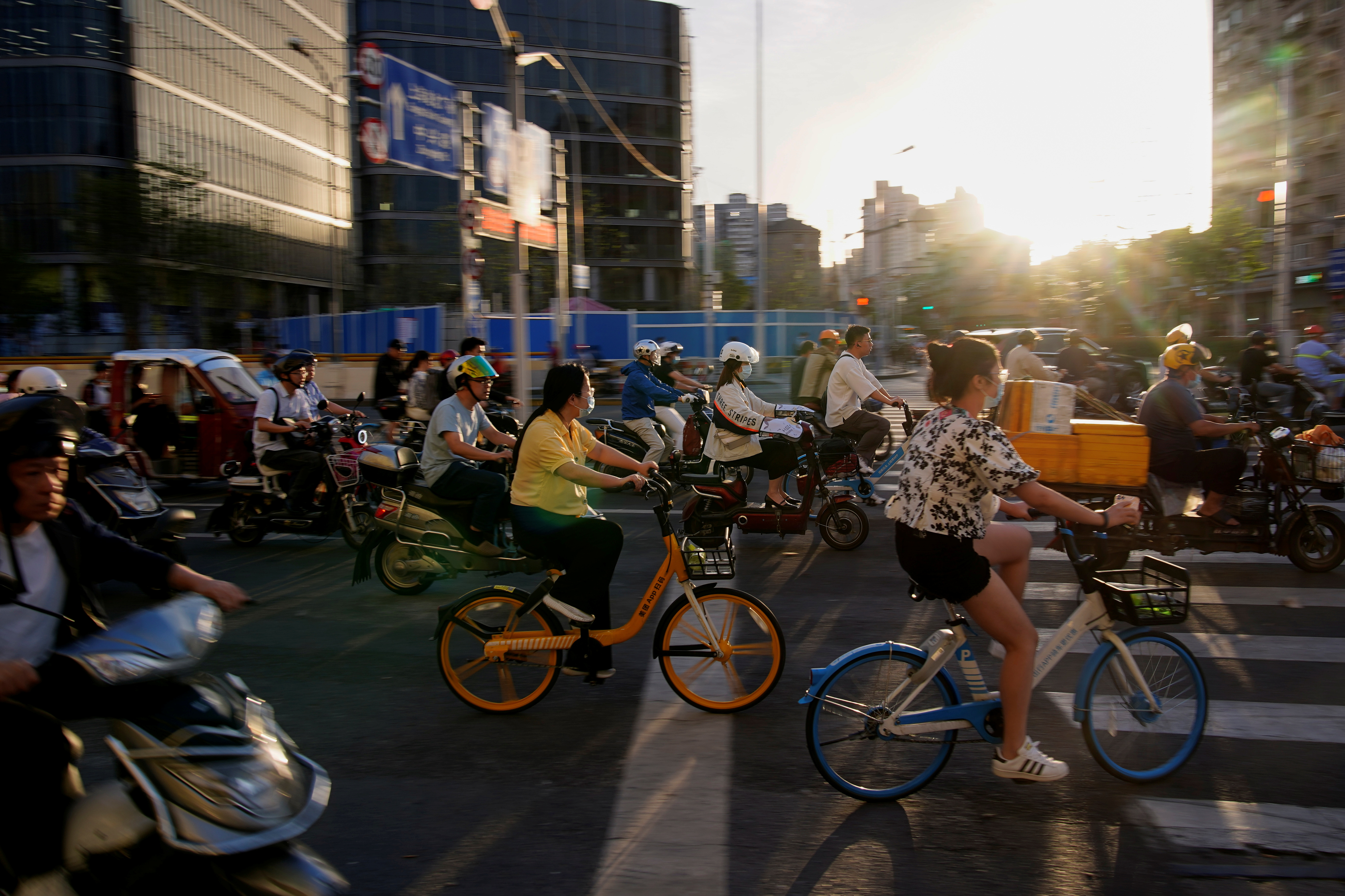 People ride bicycles and motorbikes on a street, amid the coronavirus disease pandemic, in Shanghai