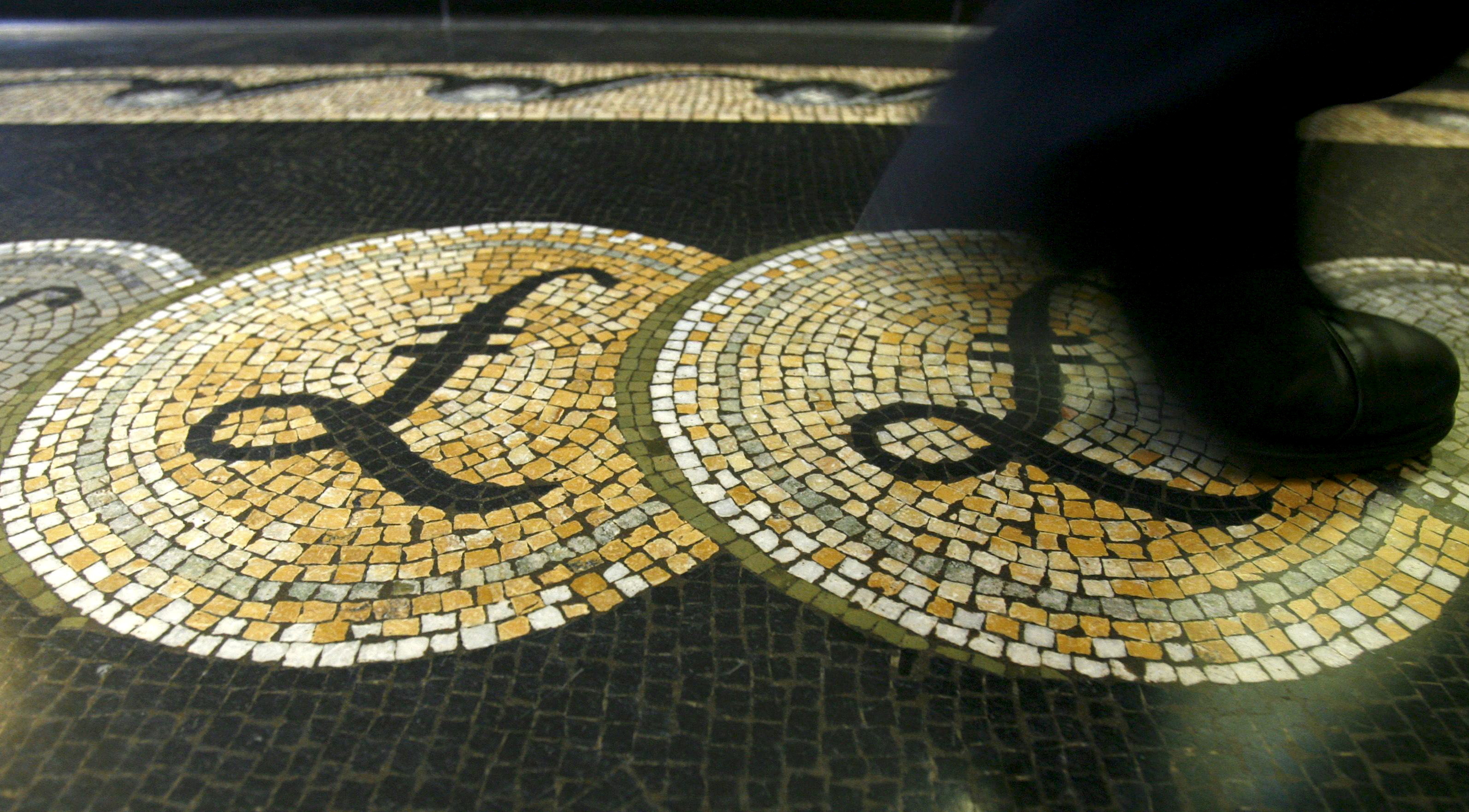 File photograph shows an employee walking over a mosaic depicting pound sterling symbols on the floor of the front hall of the Bank of England in London