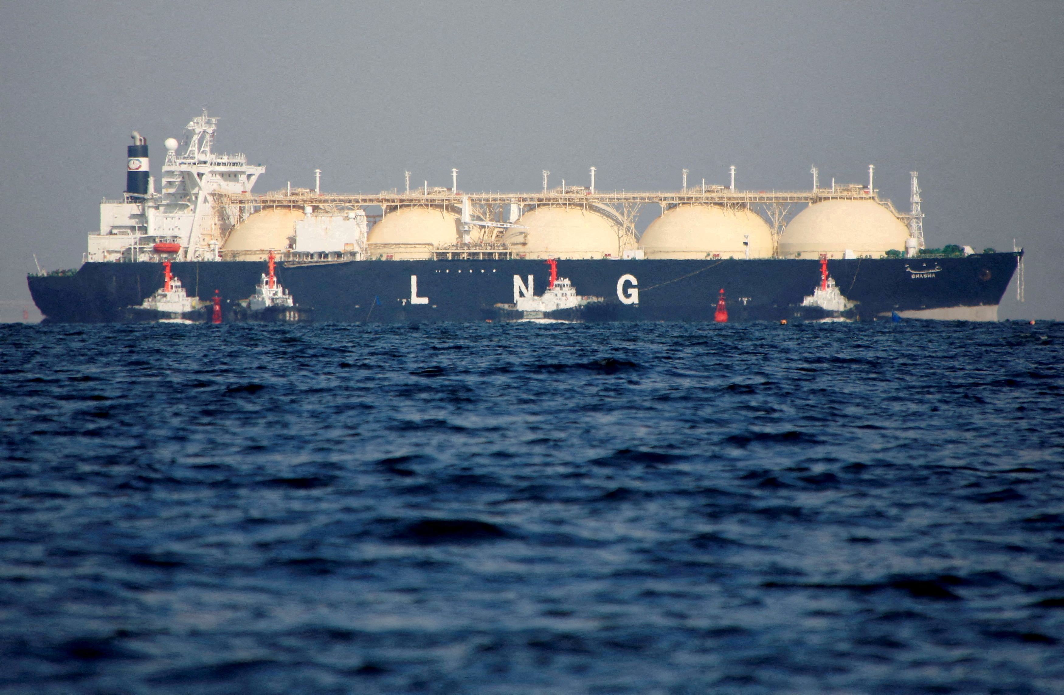 An LNG tanker is tugged towards a thermal power station in Futtsu