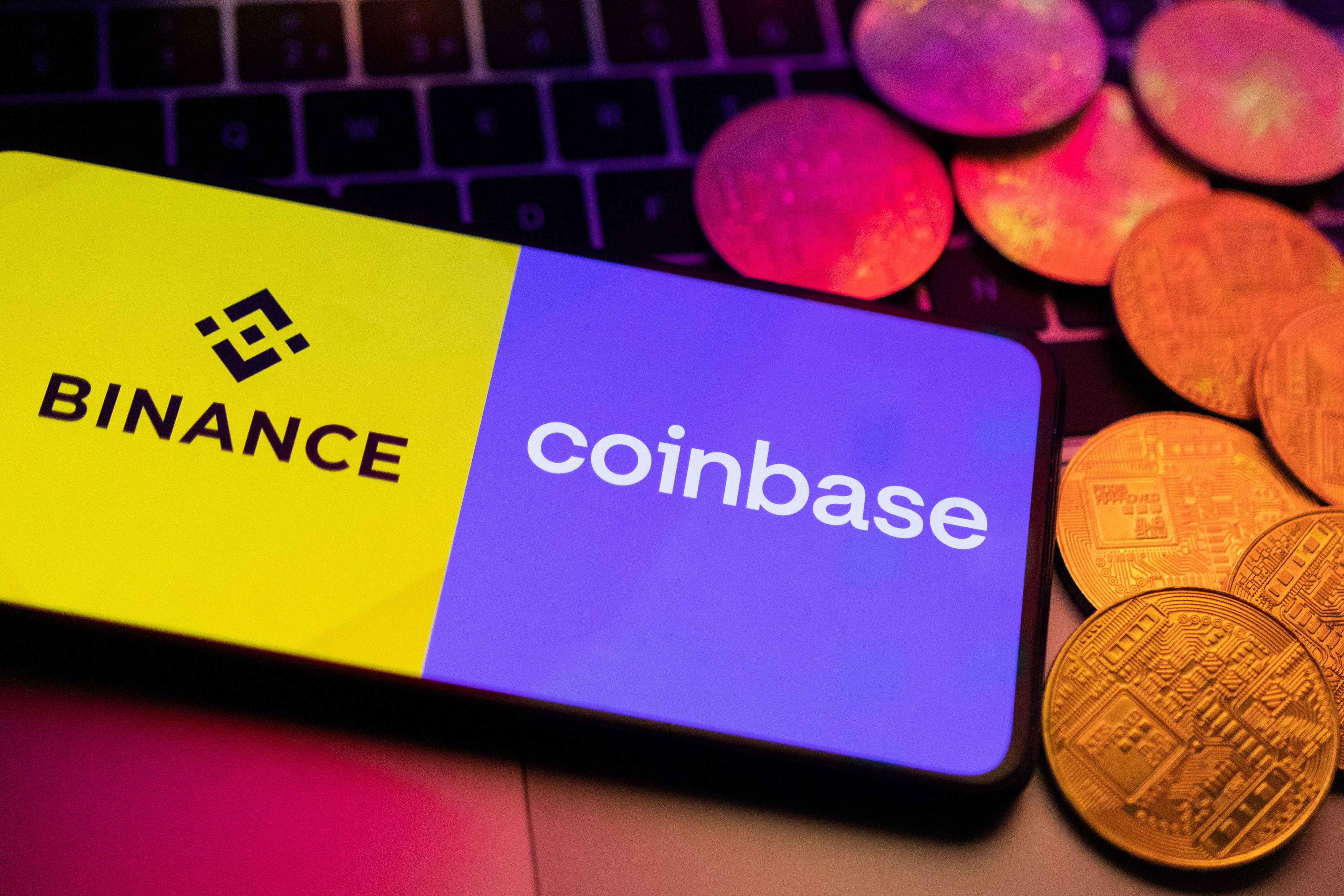Illustration shows smartphone with displayed Binance and Coinbase logos