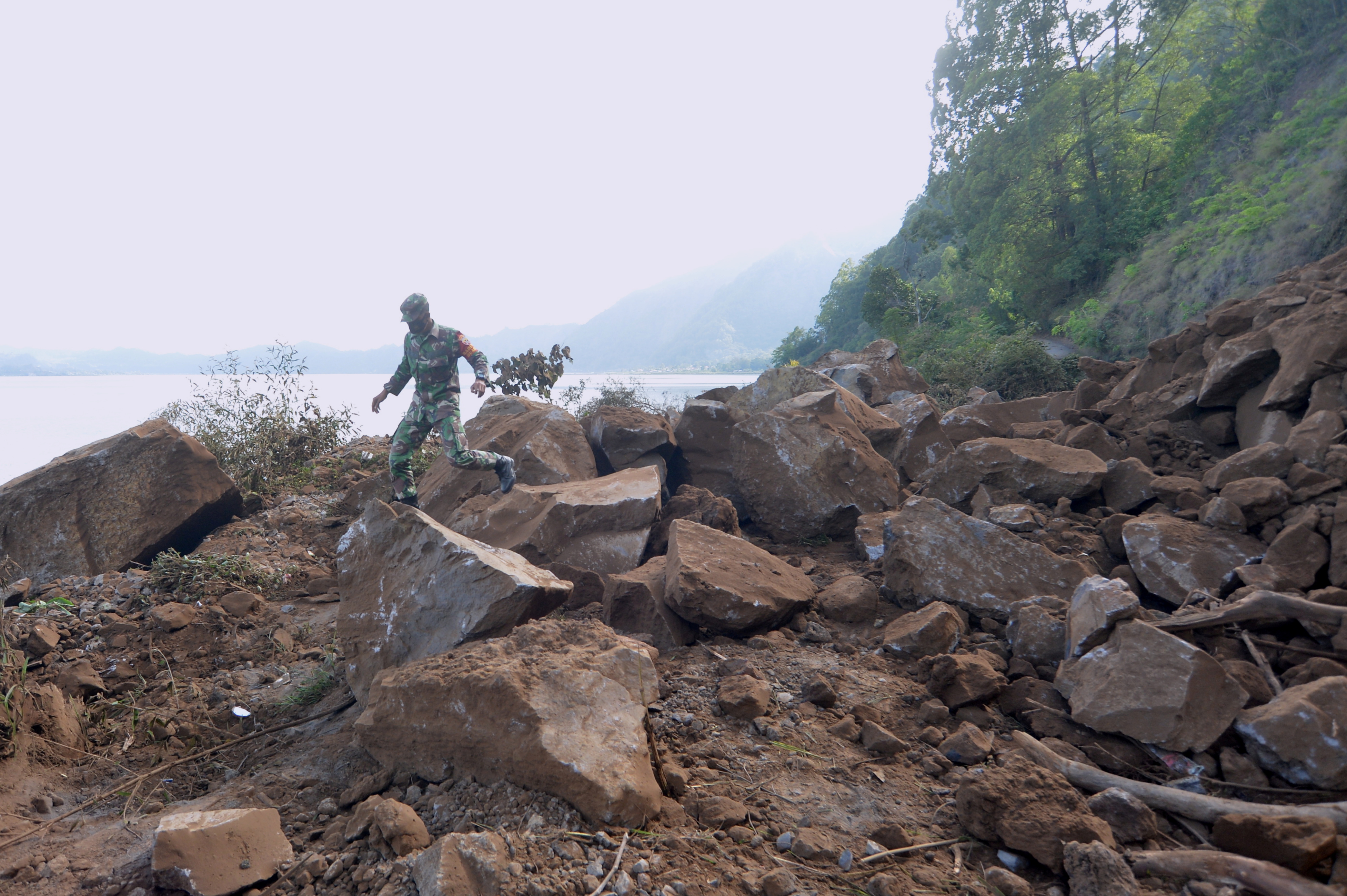 A member of Indonesian military walks through a landslide area after a 4.8 magnitude earthquake struck northeast of Bali