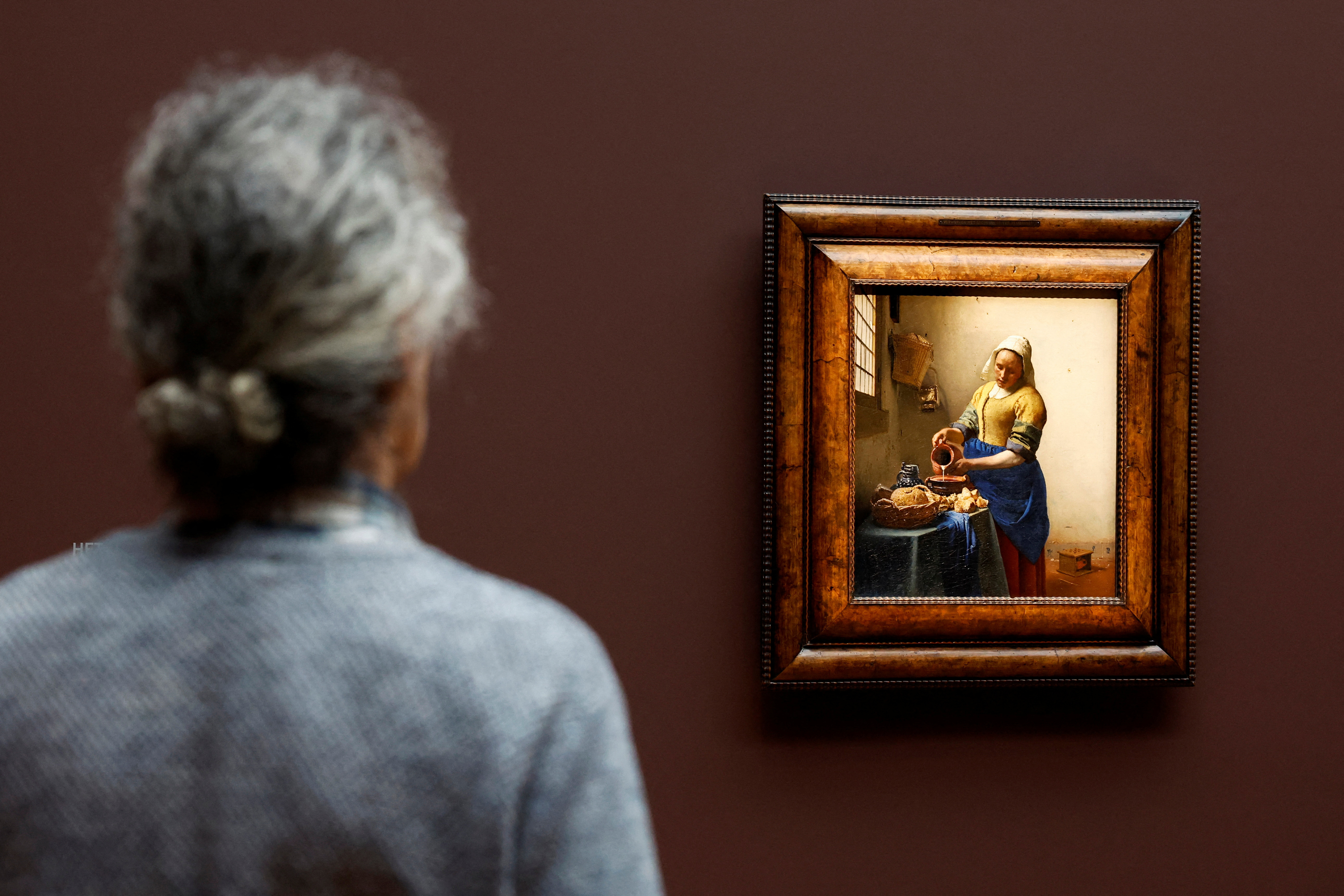 A man looks at Vermeer's painting 'The Milkmaid' at an exhibition bringing together 28 works by Dutch painter Johannes Vermeer