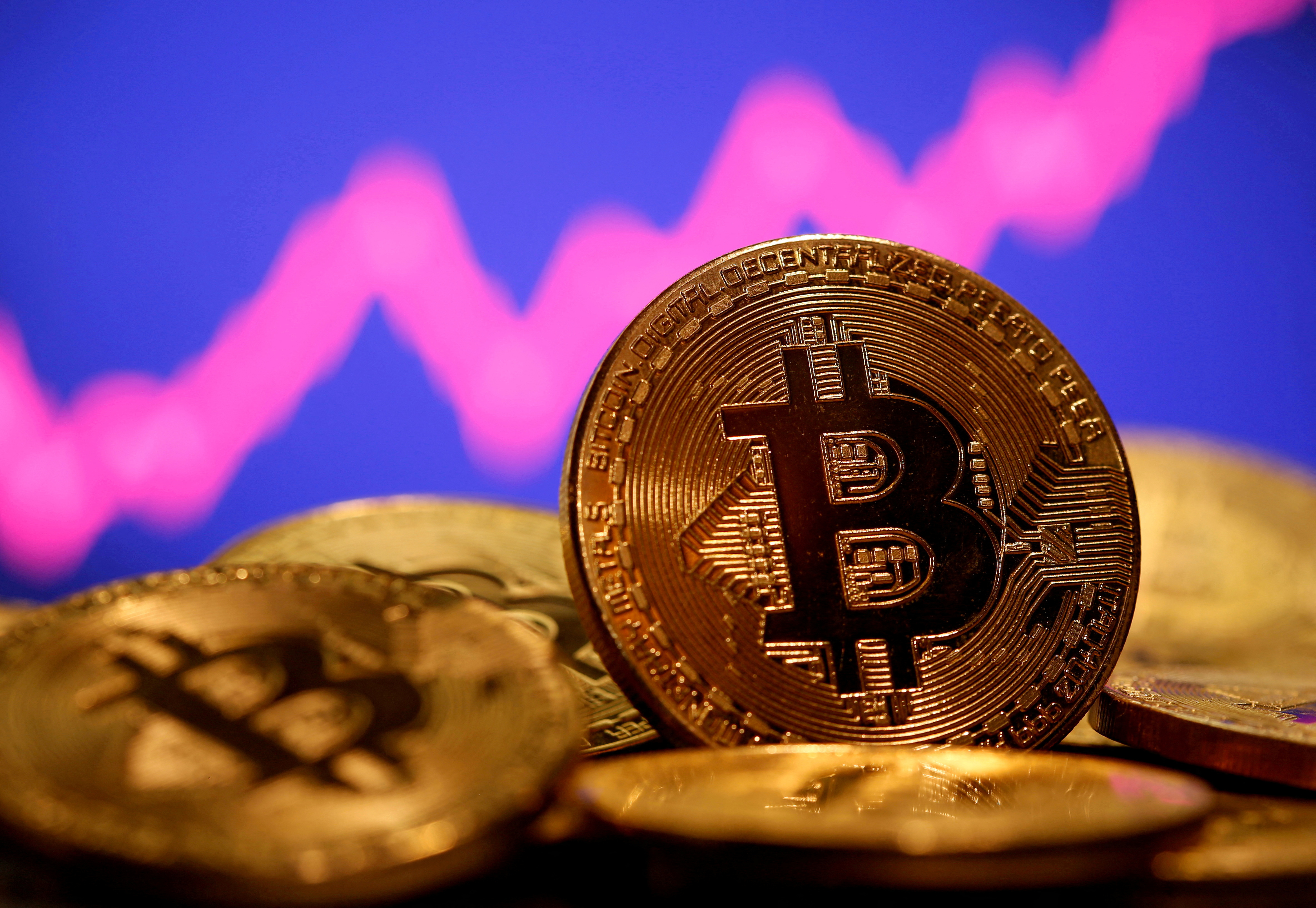 A representation of virtual currency Bitcoin is seen in front of a stock graph in this illustration taken