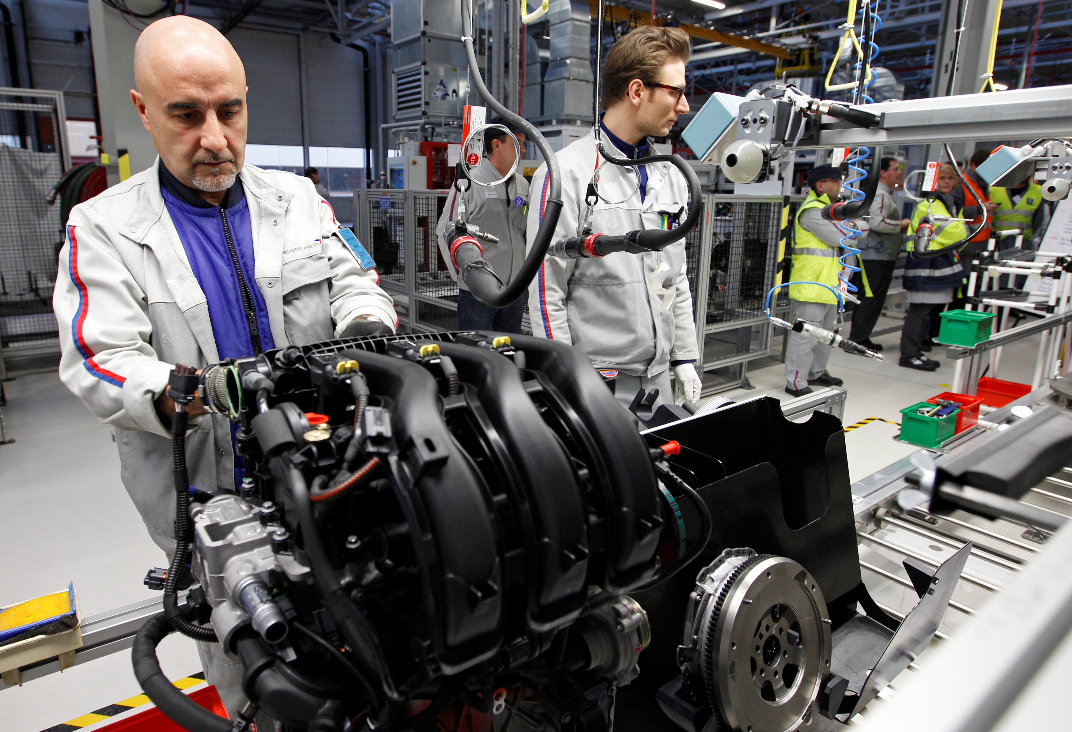 Employees of French carmaker PSA Peugeot Citroen work on the new engine 