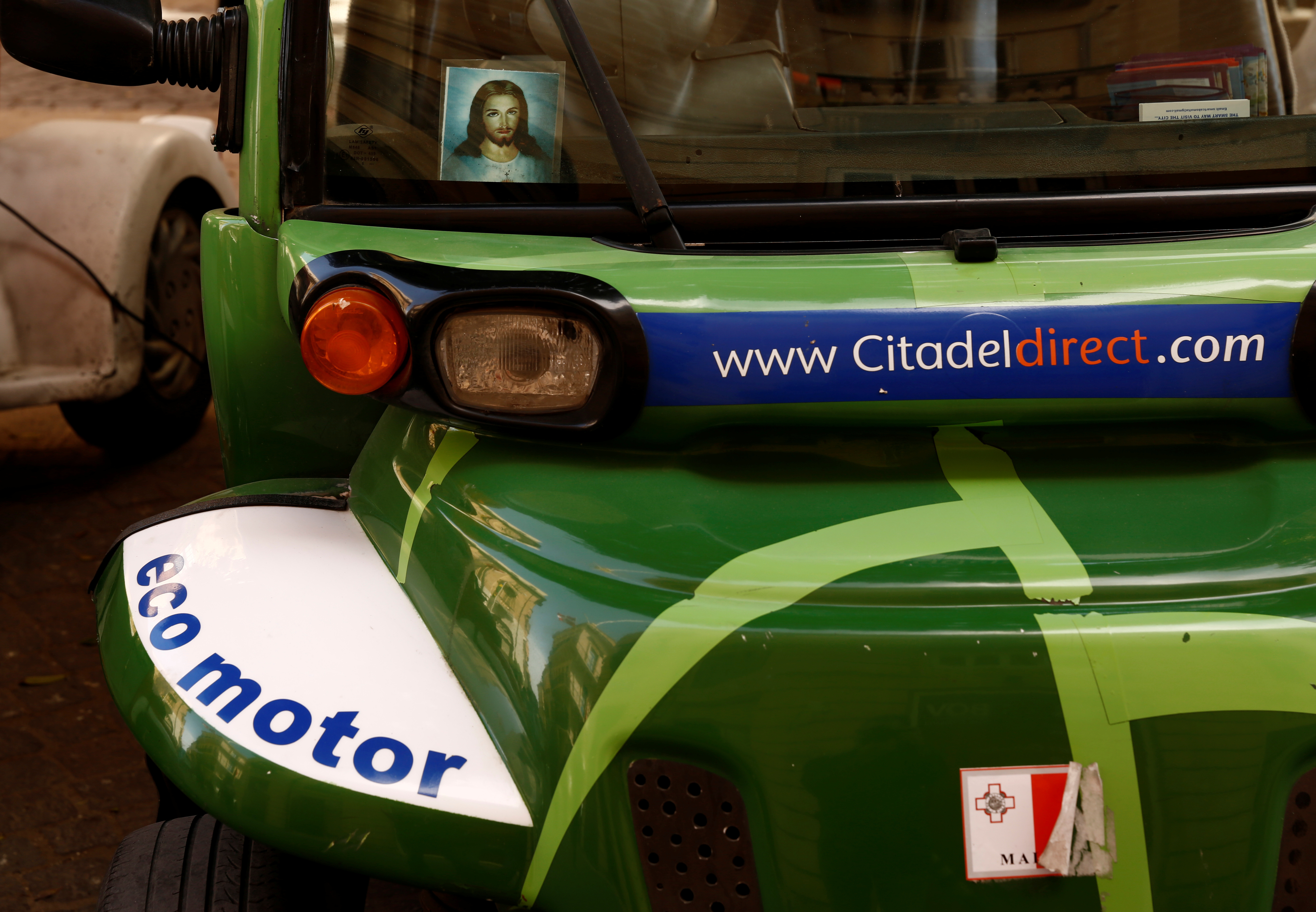A religious picture showing Jesus Christ is seen behind the windscreen of an electric cab in Valletta