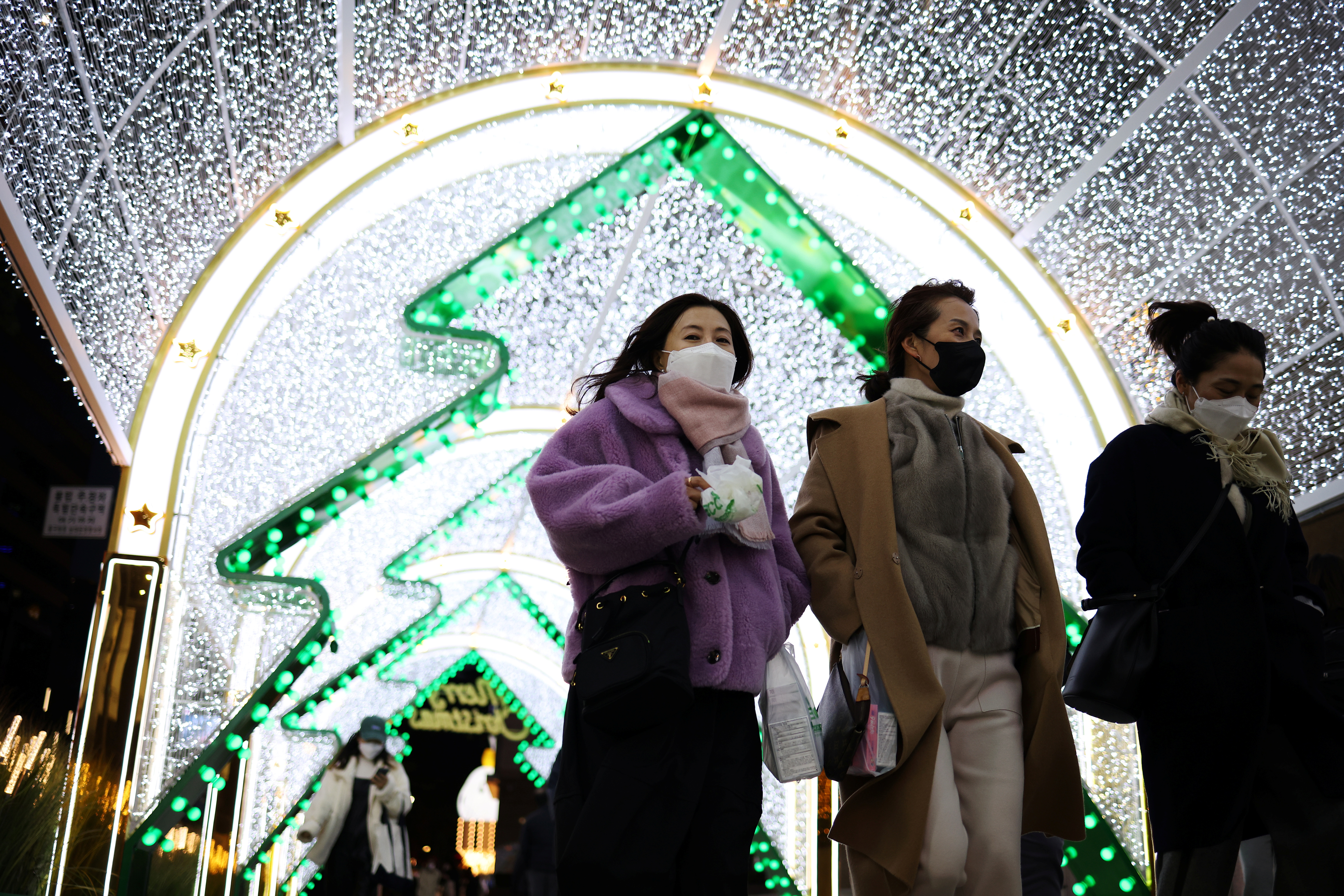 Women wearing masks to prevent contracting the coronavirus disease (COVID-19) walk under a Christmas illumination at a shopping district in central Seoul, South Korea, December 1, 2021. REUTERS/Kim Hong-Ji