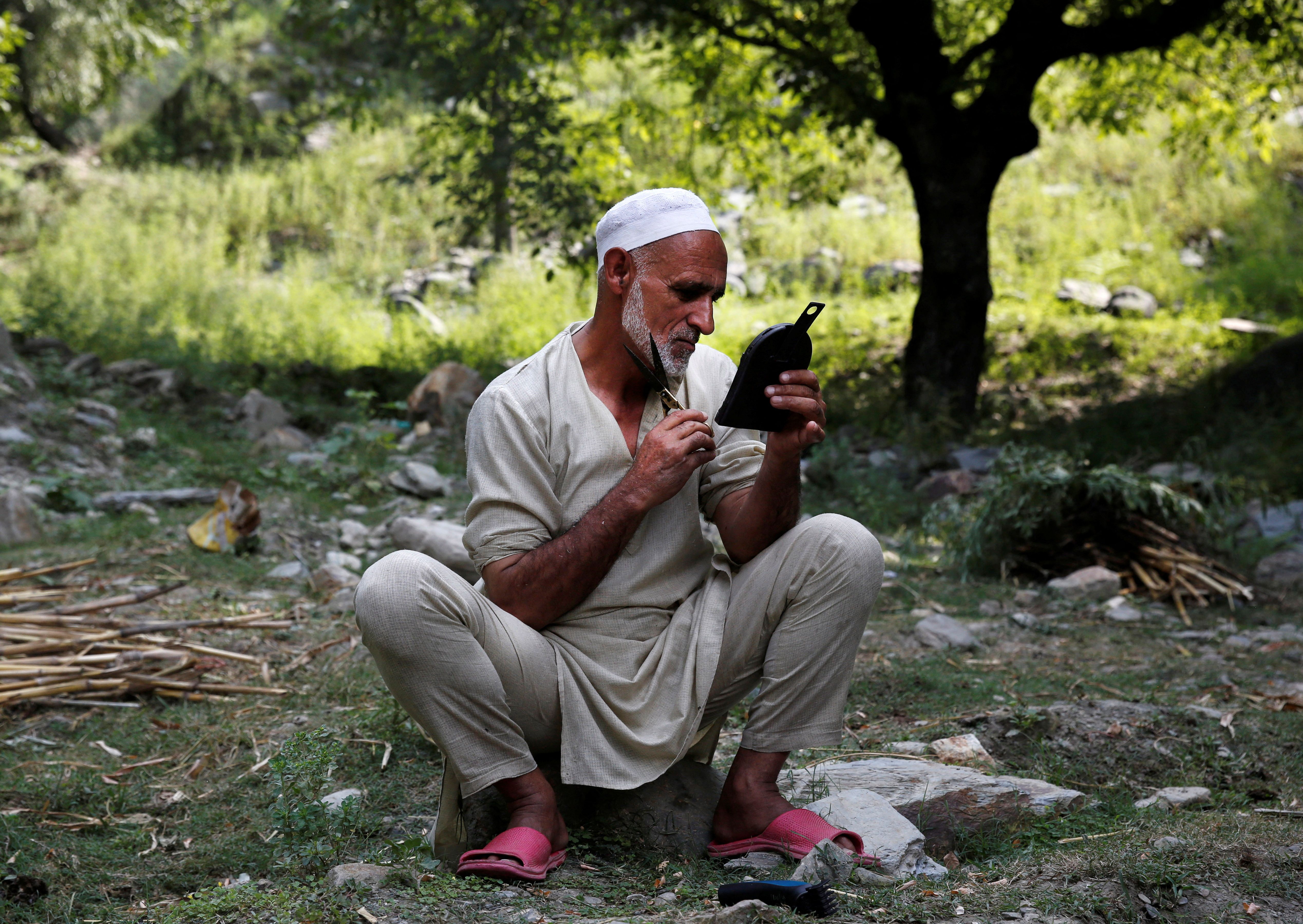 A villager trims his beard outside his house in Teetwal near the Line of Control between India and Pakistan in Teetwal