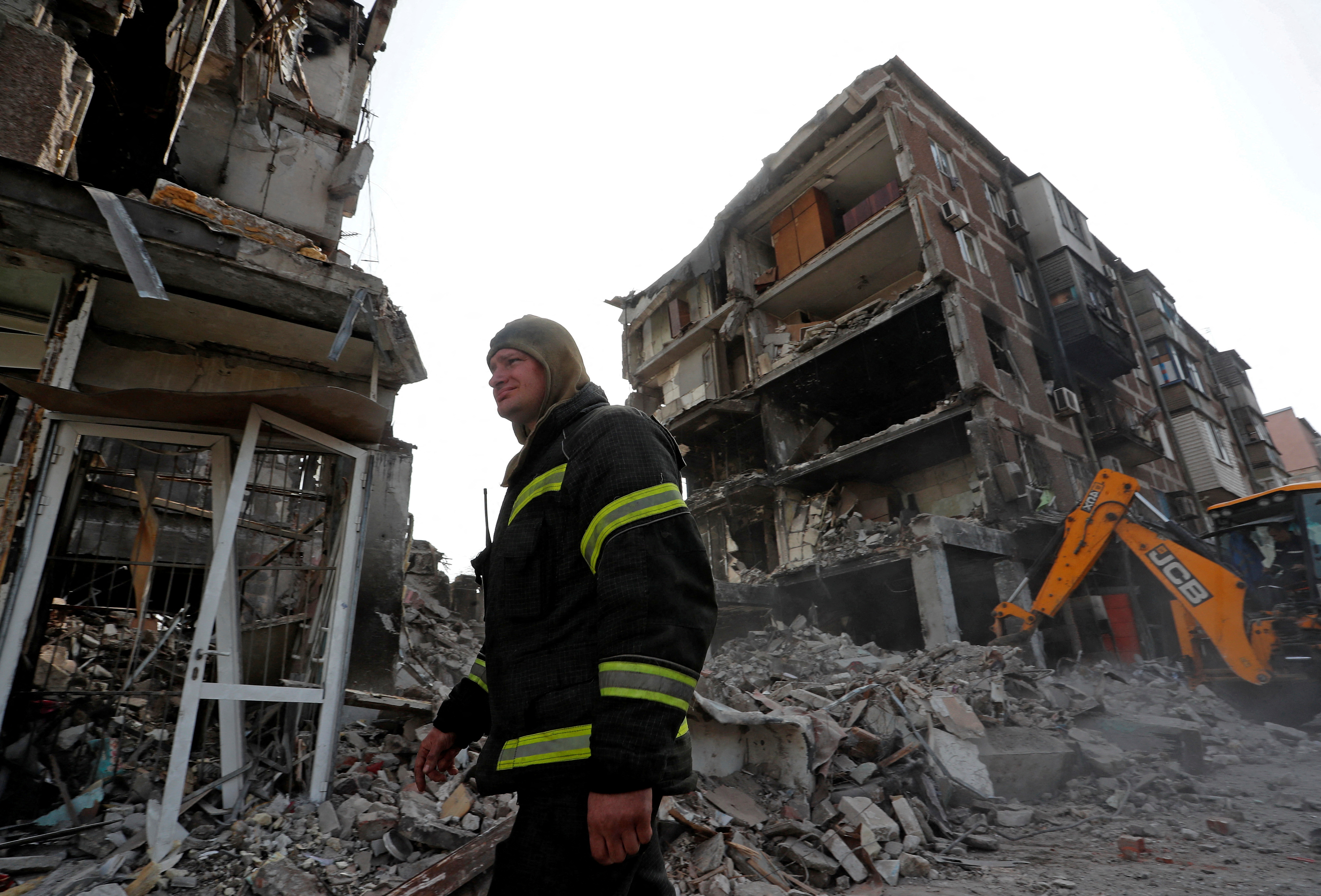 A rescuer works at a damaged residential building in Mariupol