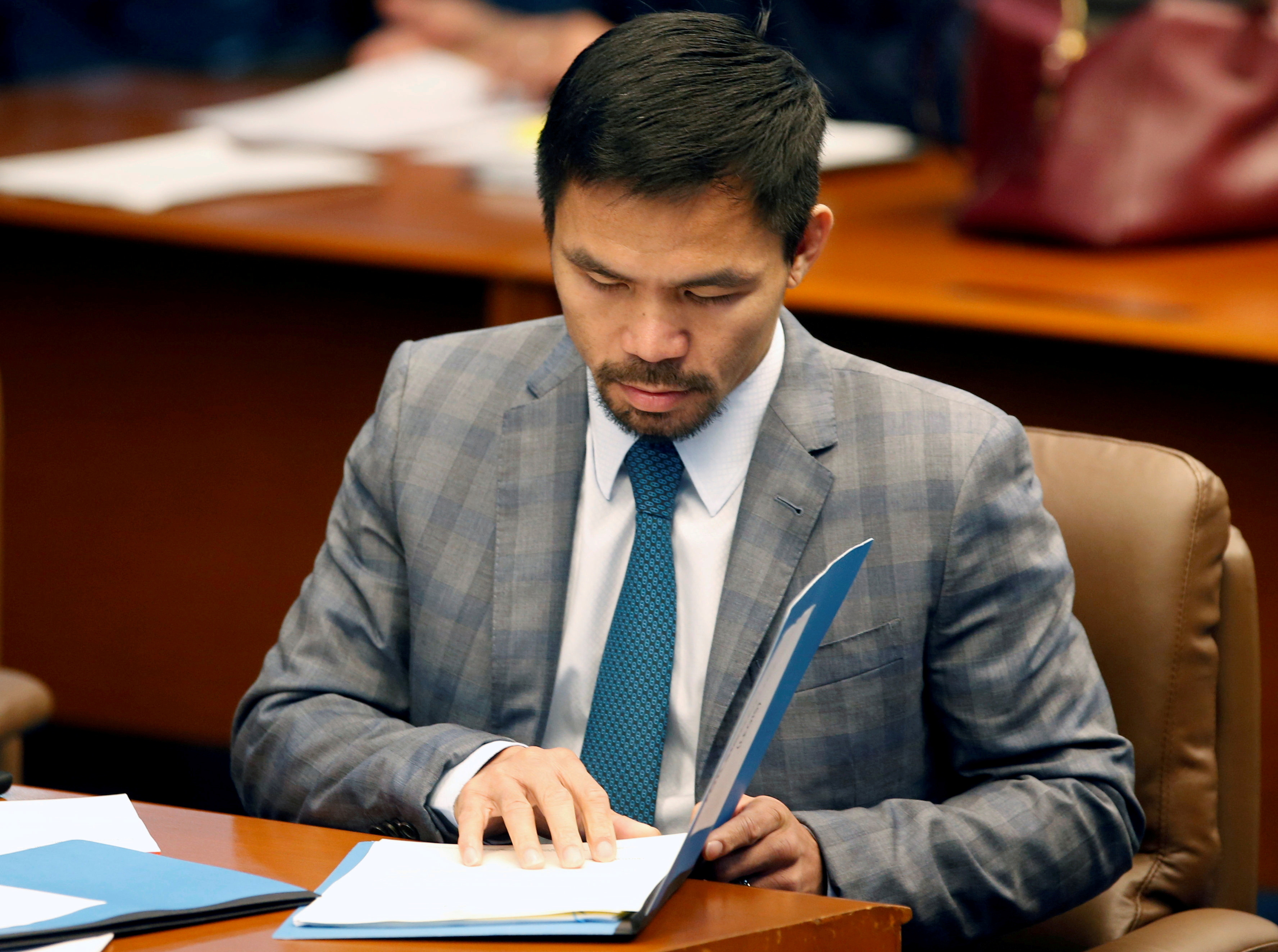Philippine Senator and boxing champion Manny Pacquiao reads his briefing materials as he prepares for the Senate session in Pasay city, Metro Manila