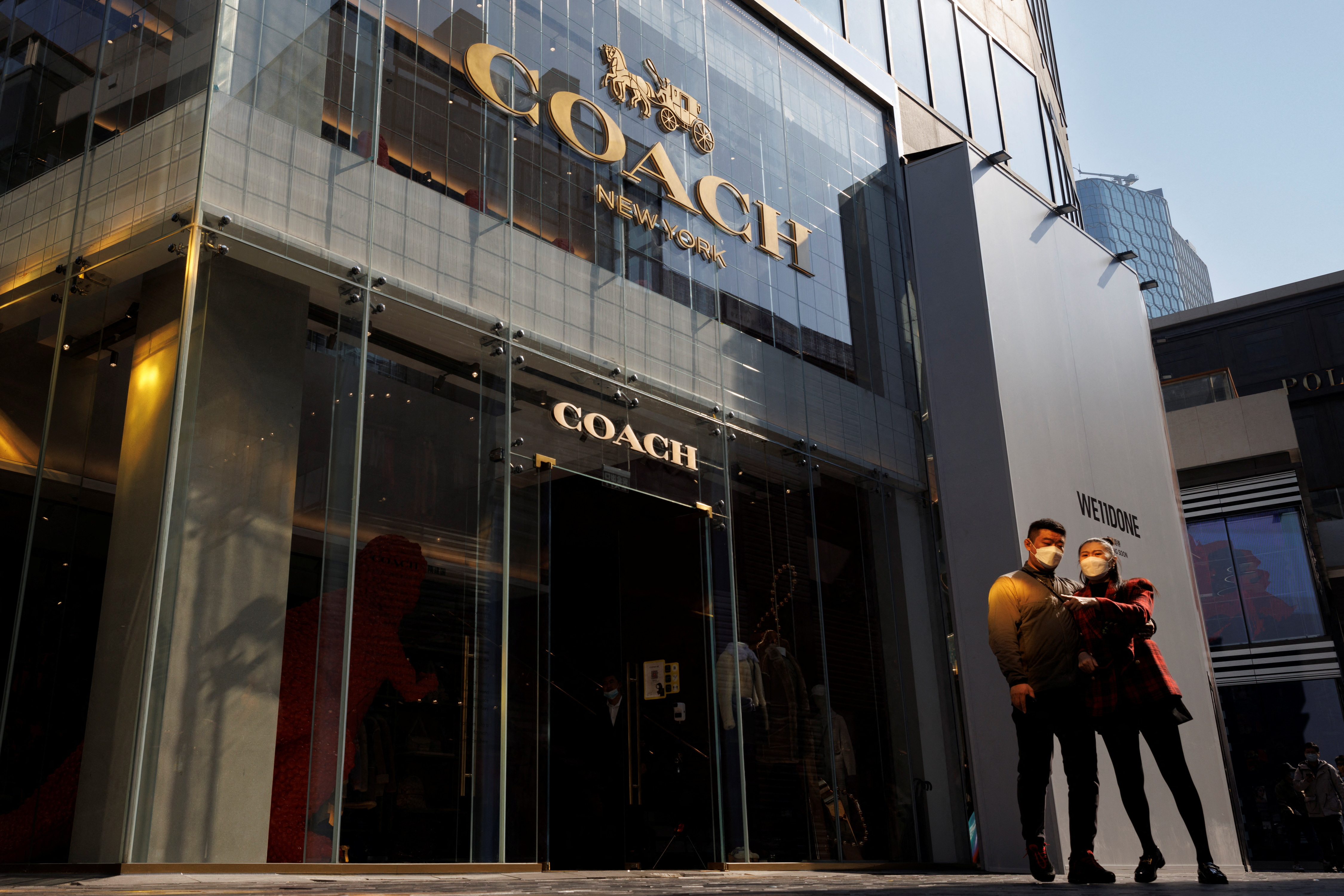 People walk past a store of the Coach luxury fashion retailer in a shopping district in Beijing