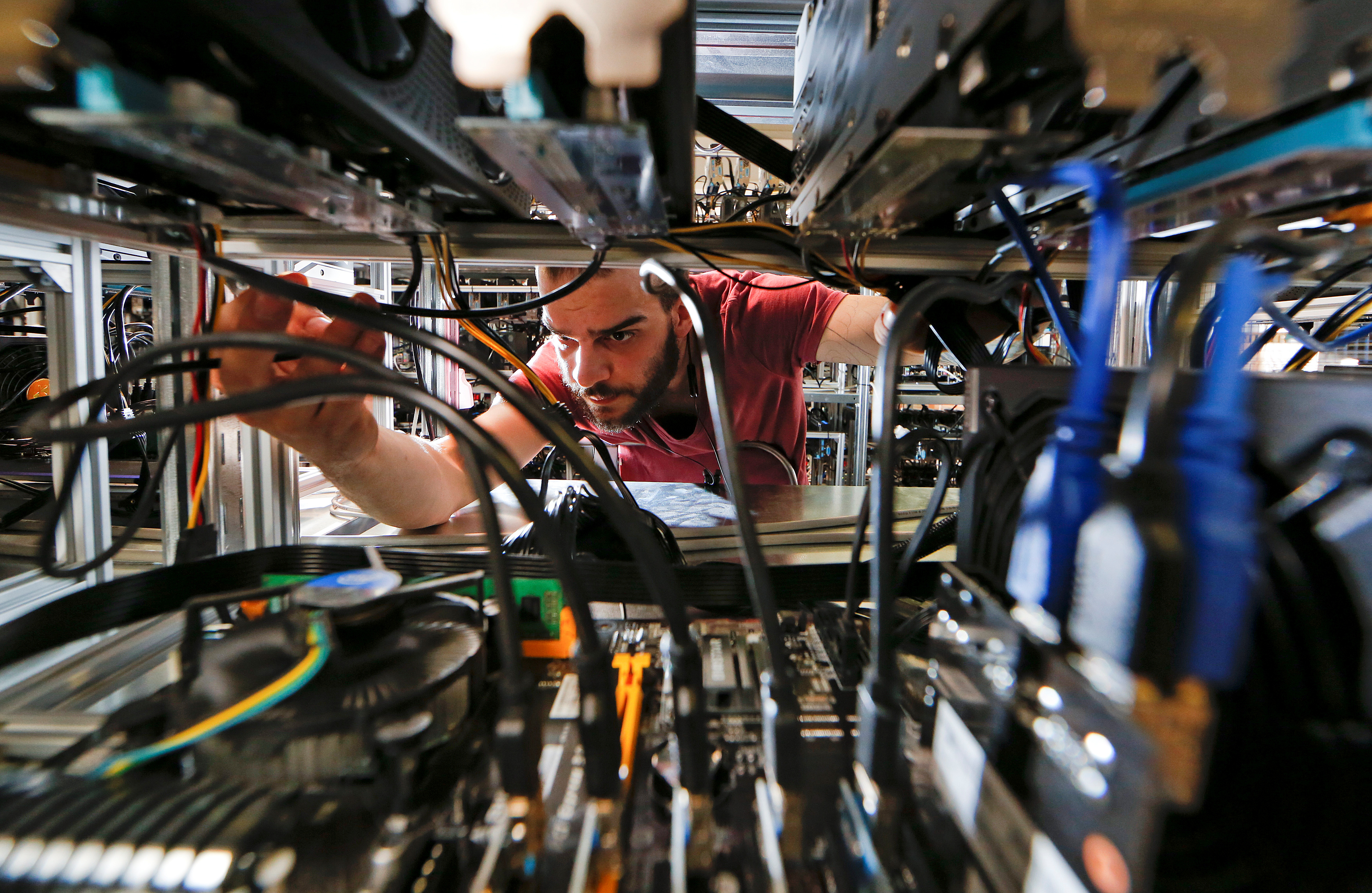 An employee works on bitcoin mining computers at Bitminer factory in Florence, Italy, April 9, 2018. Picture taken April 9, 2018. REUTERS/Alessandro Bianchi - RC1331747750