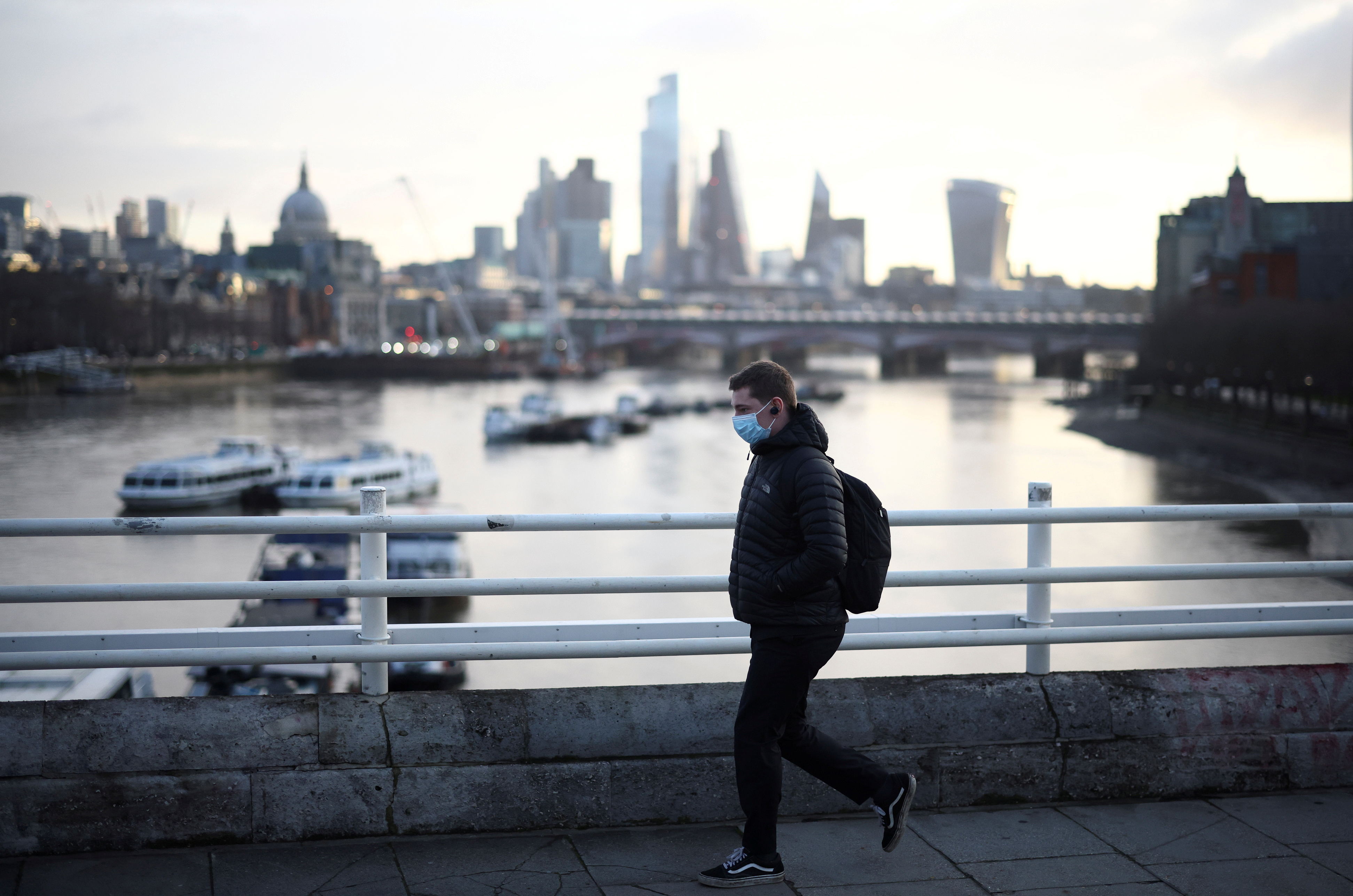 A man wearing a protective face mask walks across Waterloo Bridge, amid the coronavirus disease (COVID-19) outbreak in London, Britain