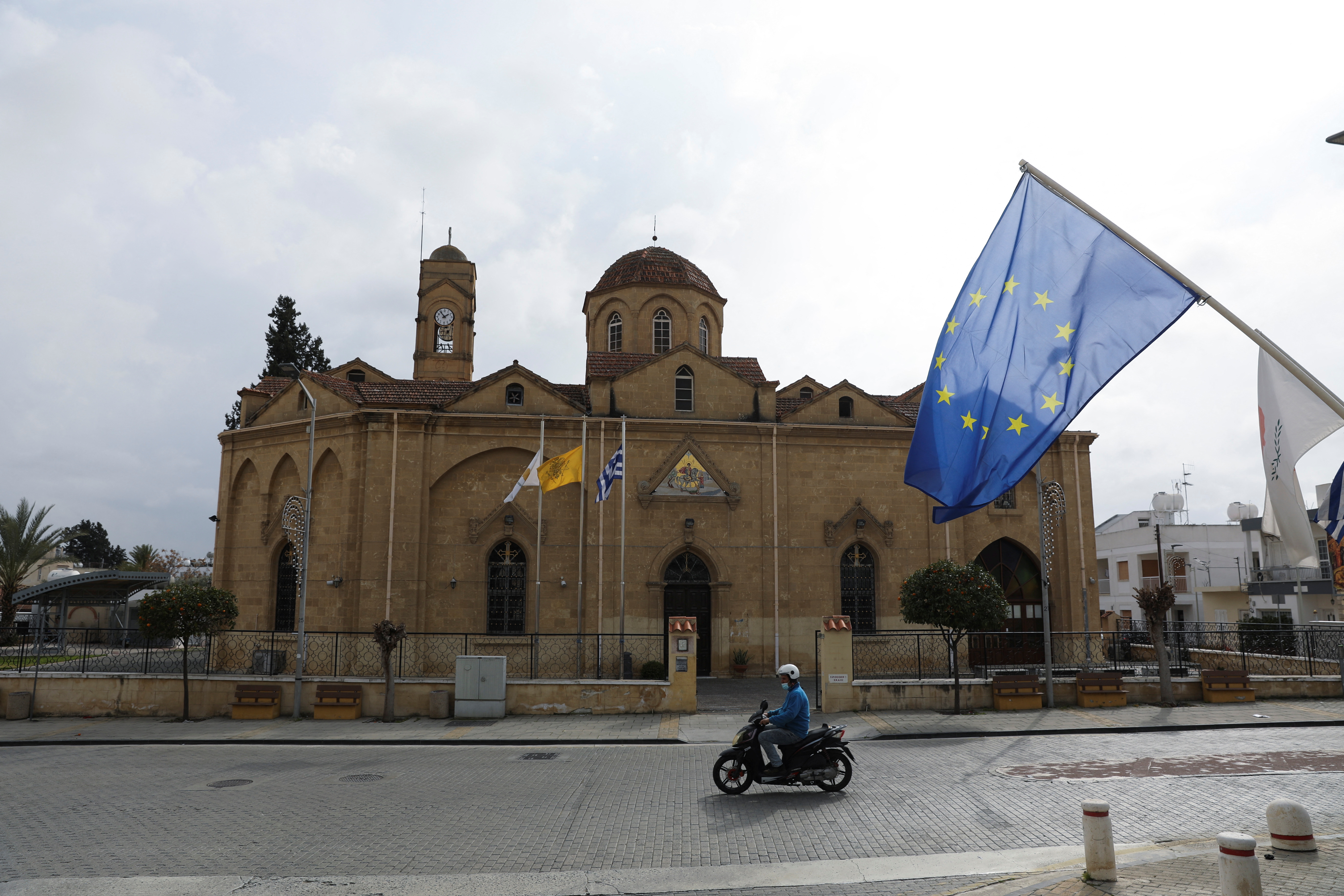 A man rides his motorcycle in front of the church of St. George in the Ayios Dhometios suburb of Nicosia