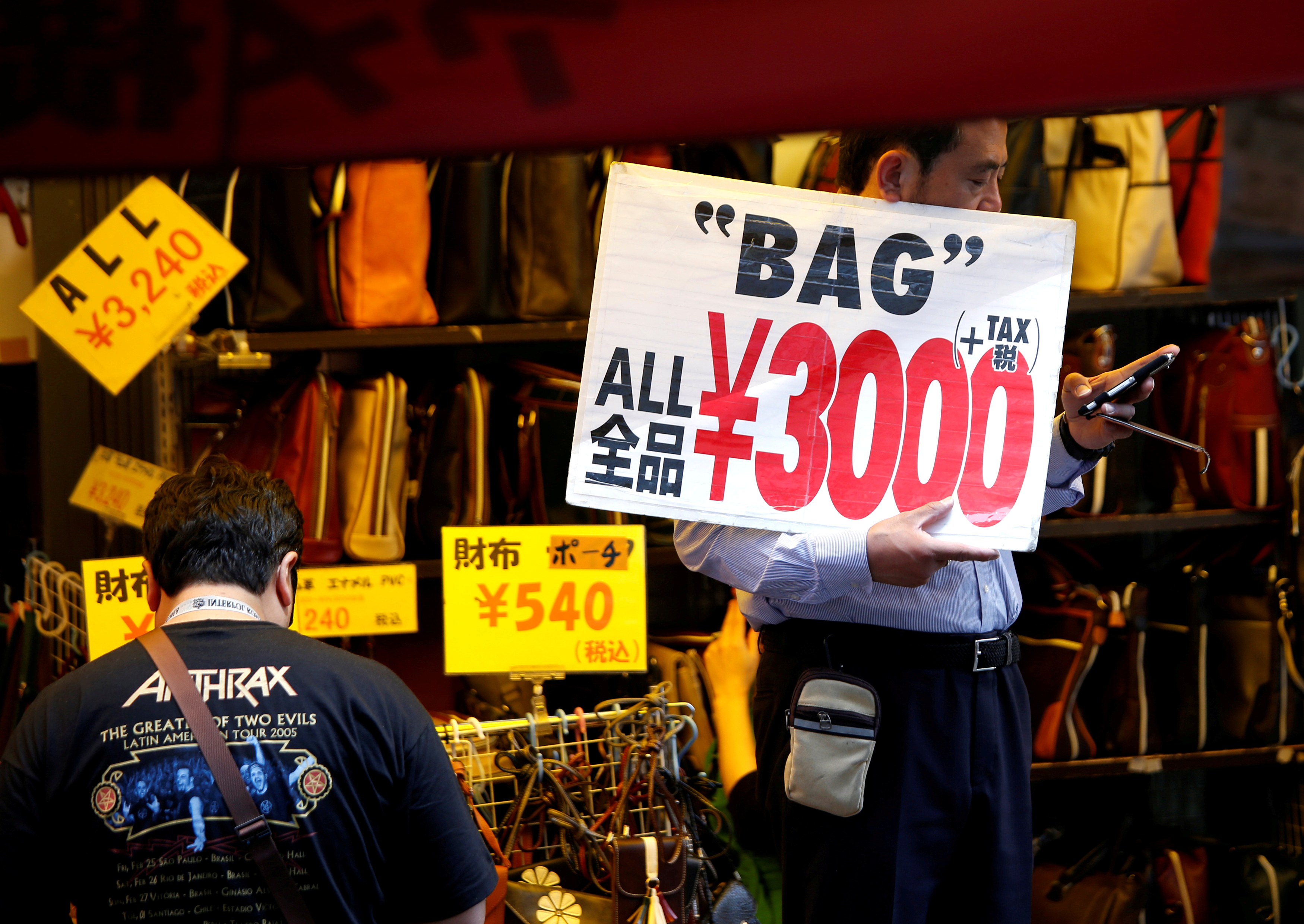 FILE PHOTO: A shop employee holds a placard to attract costomers in Tokyo