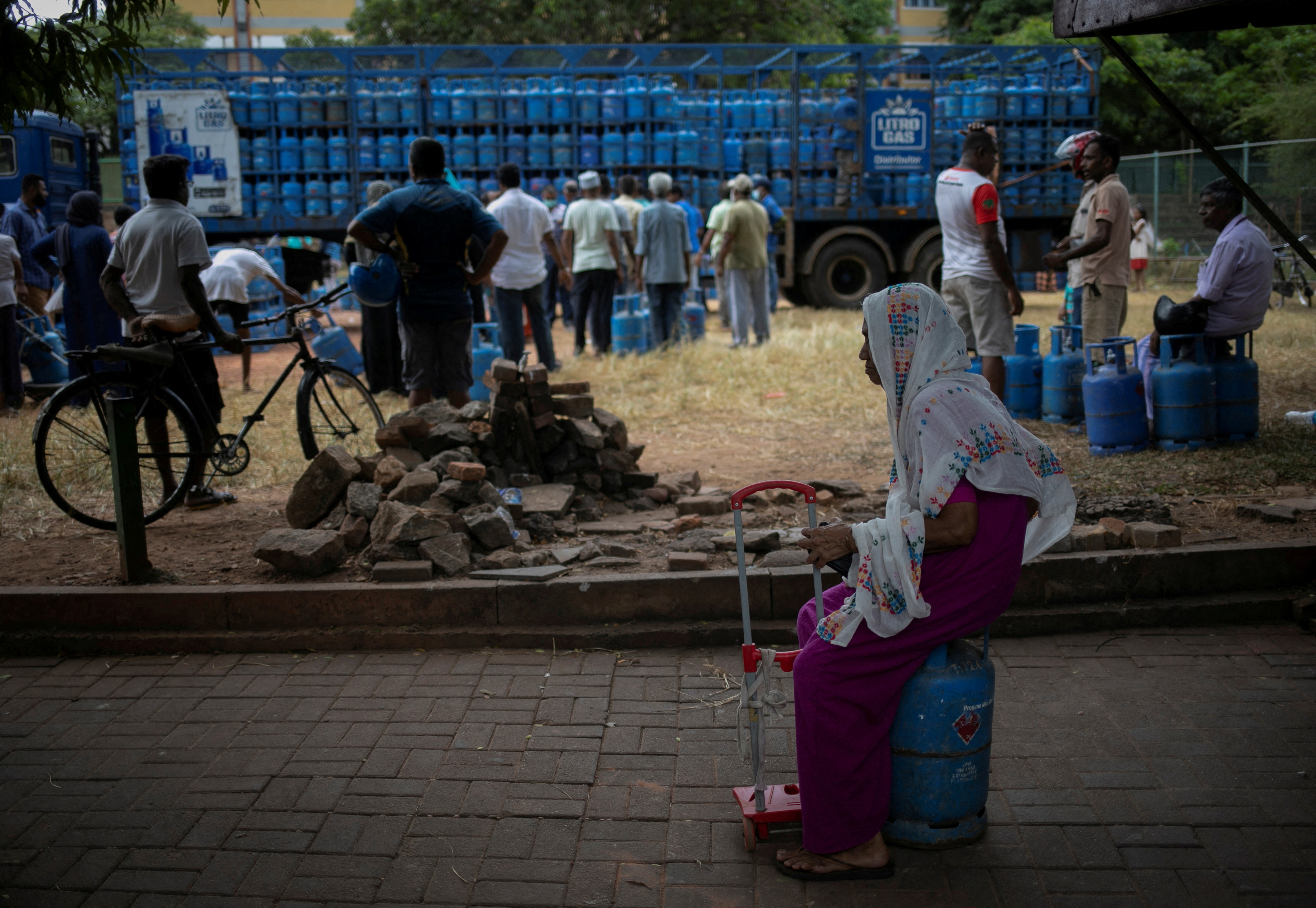 A woman sits on an empty domestic cooking gas cylinder at a distribution centre, amid the country's economic crisis, in Colombo